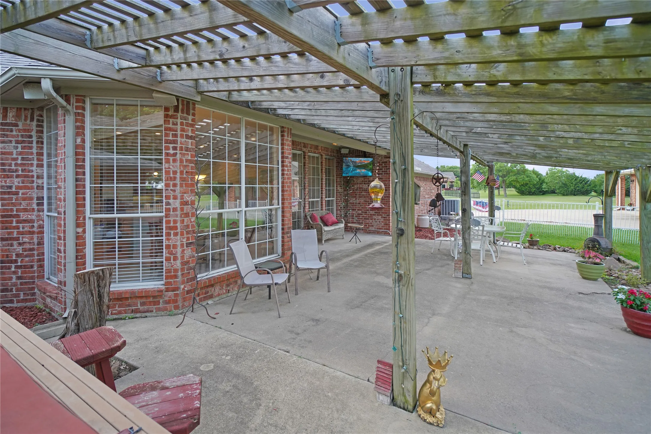 Expansive patio featuring a wooden pergola, concrete flooring, and brick exterior