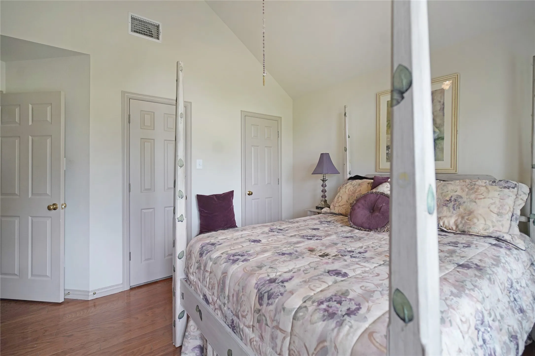 Vaulted ceiling bedroom featuring wood-finish flooring