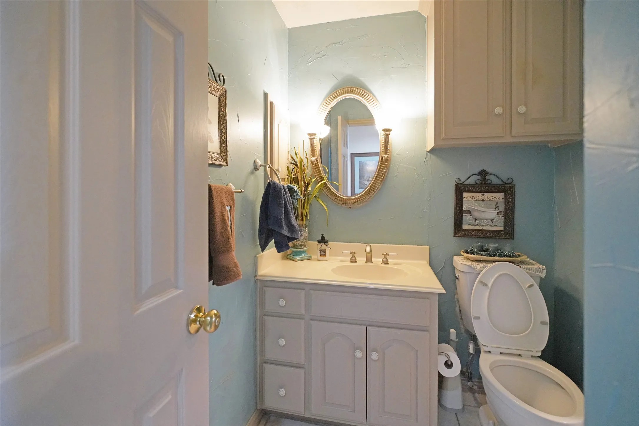 Bathroom featuring a single vanity with storage cabinetry, a wall-mounted mirror, and overhead lighting