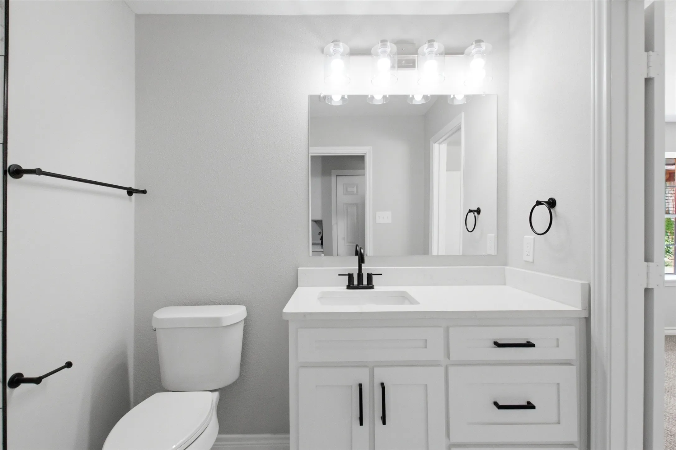 Bathroom featuring a white vanity with slab countertop, undermount sink, and matte black faucet