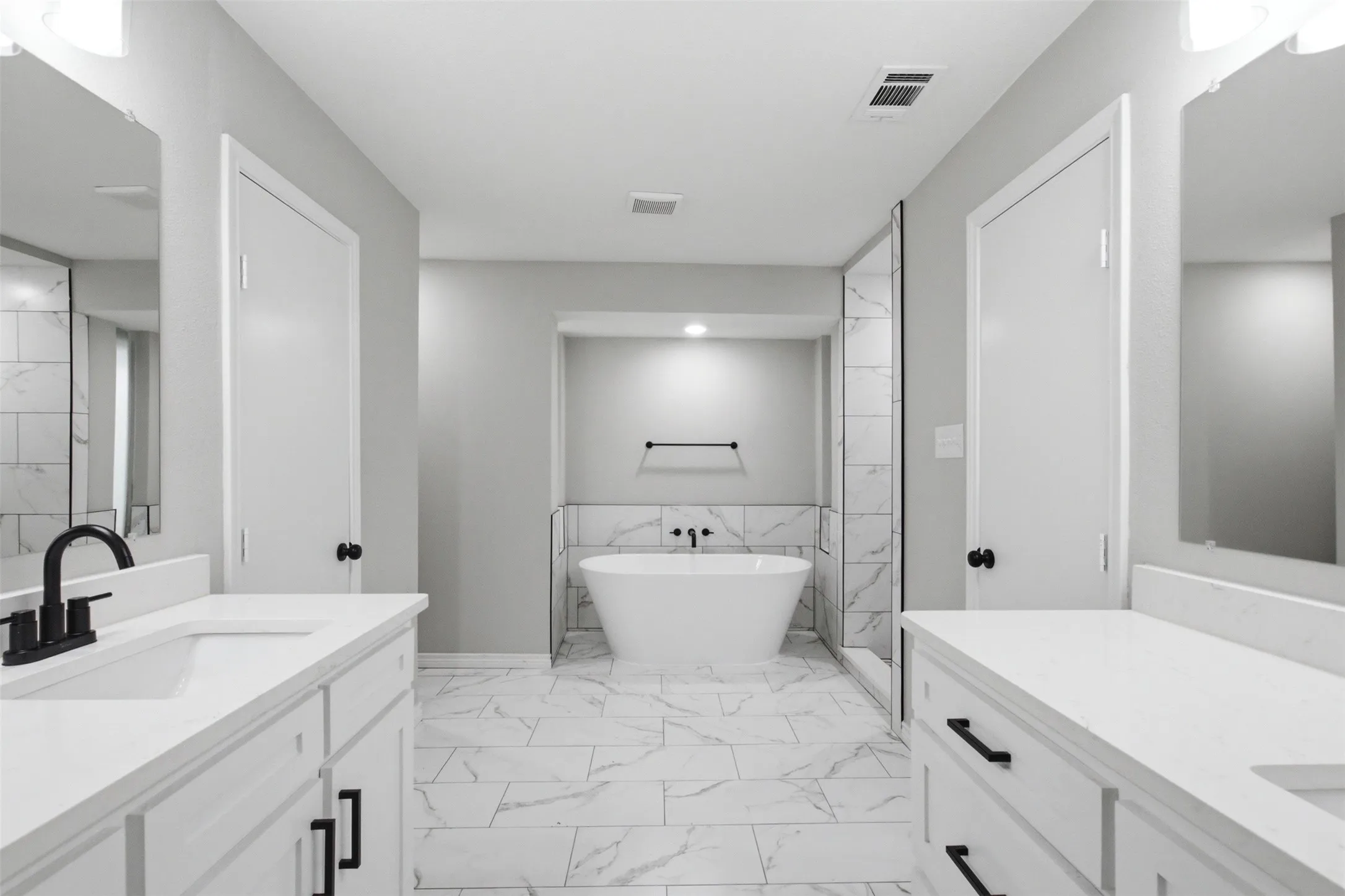Contemporary bathroom featuring a freestanding tub, a glass-enclosed shower, dual vanities with integrated sinks, and marble-look floor tiling