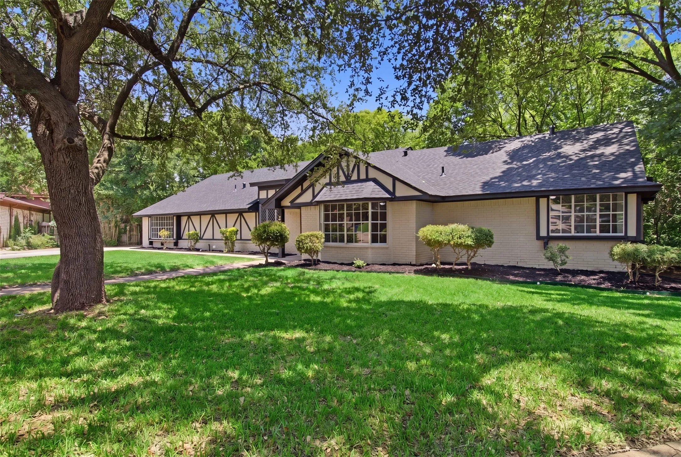 Tudor-style facade featuring cream-colored brick and dark trim accents