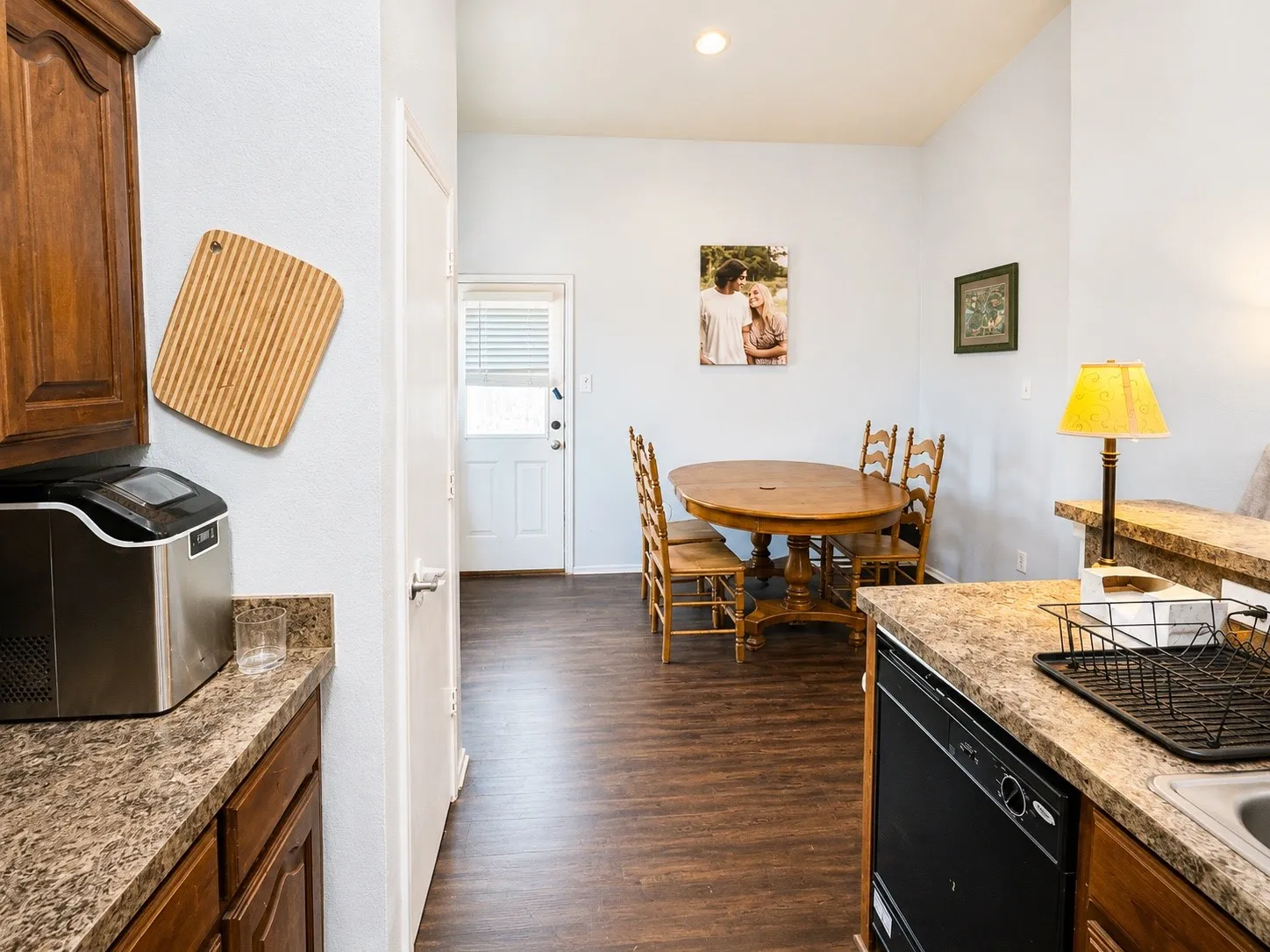 Kitchen area featuring wood-finish flooring, built-in cabinetry, and a black dishwasher