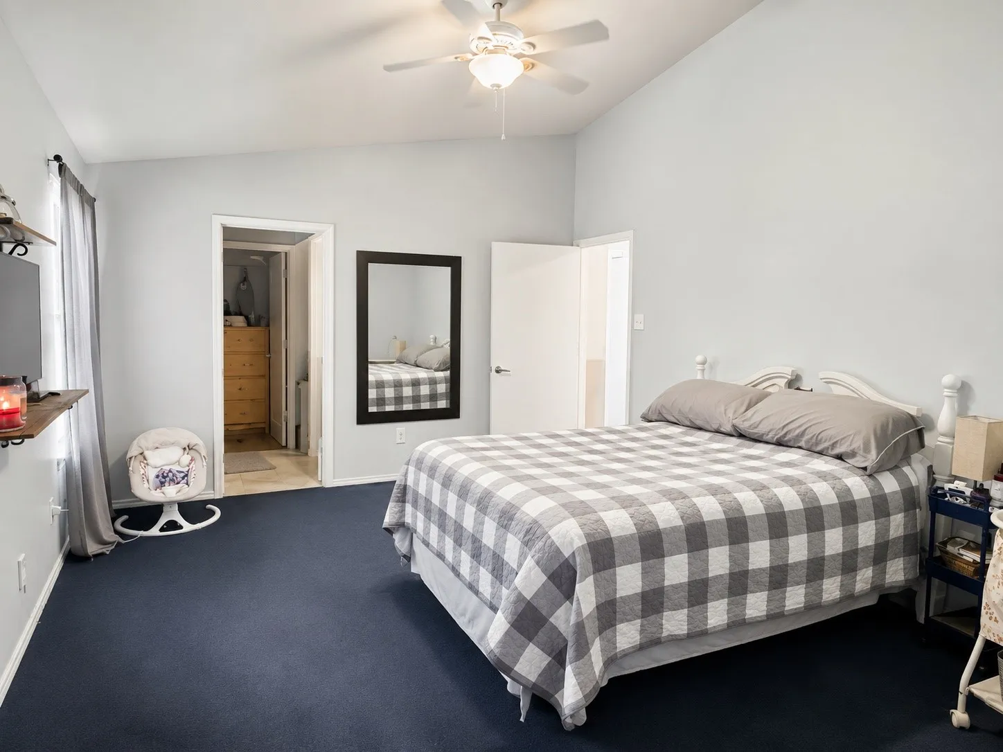 Bedroom featuring vaulted ceilings, a ceiling fan with integrated lighting, dark blue carpeting, and a closet with wood-finish built-in storage