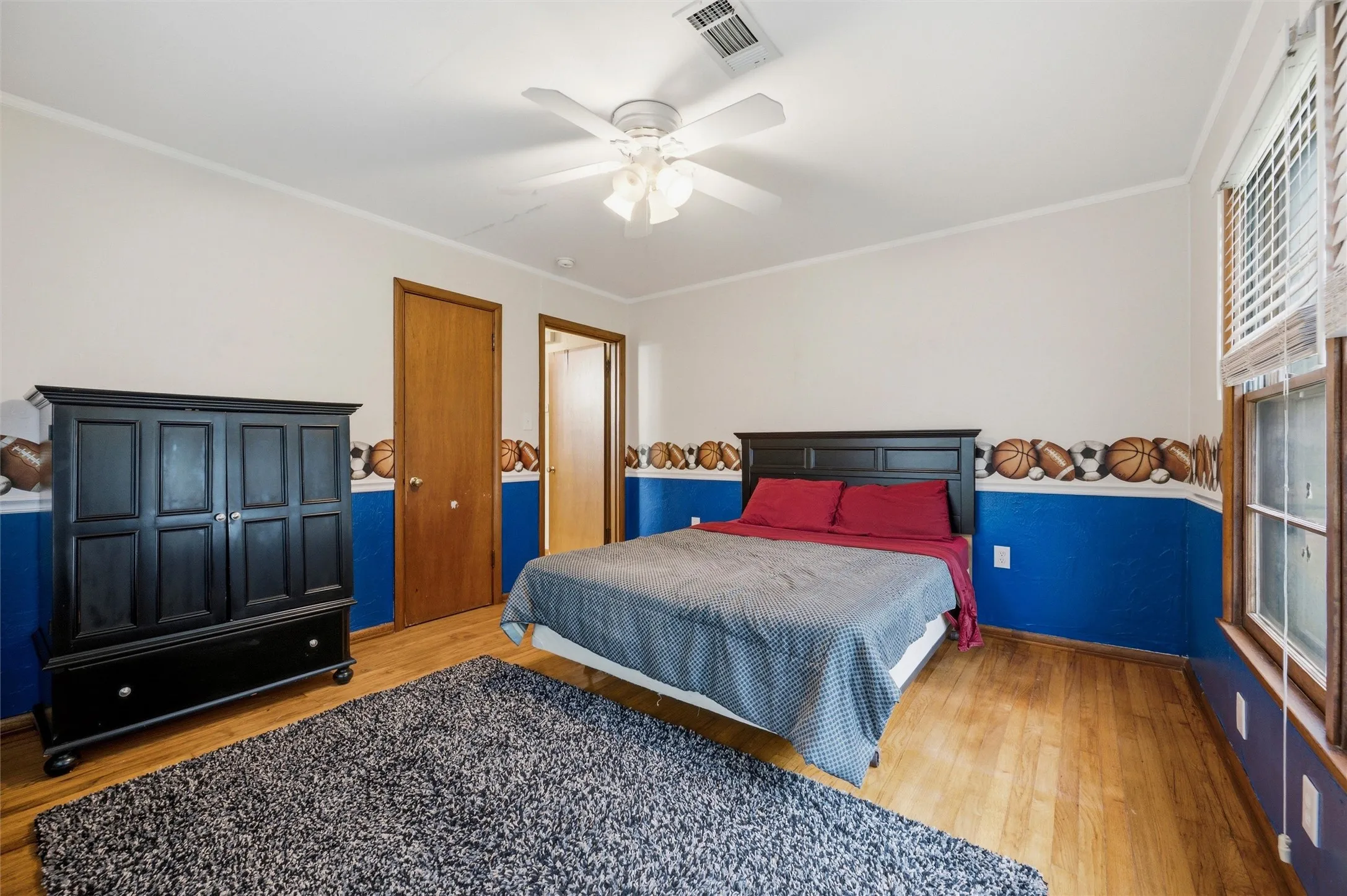 Secondary Bedroom features crown molding and a ceiling fan with light fixture. Window provides natural light. Closet door provides storage. Hardwood flooring extends throughout.