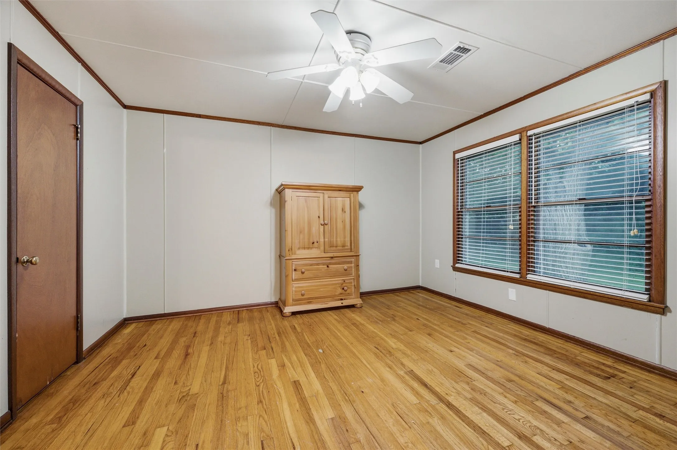 Secondary Bedroom features crown molding and a ceiling fan with light fixture. Double windows provide natural light throughout the room. Hardwood flooring extends throughout.