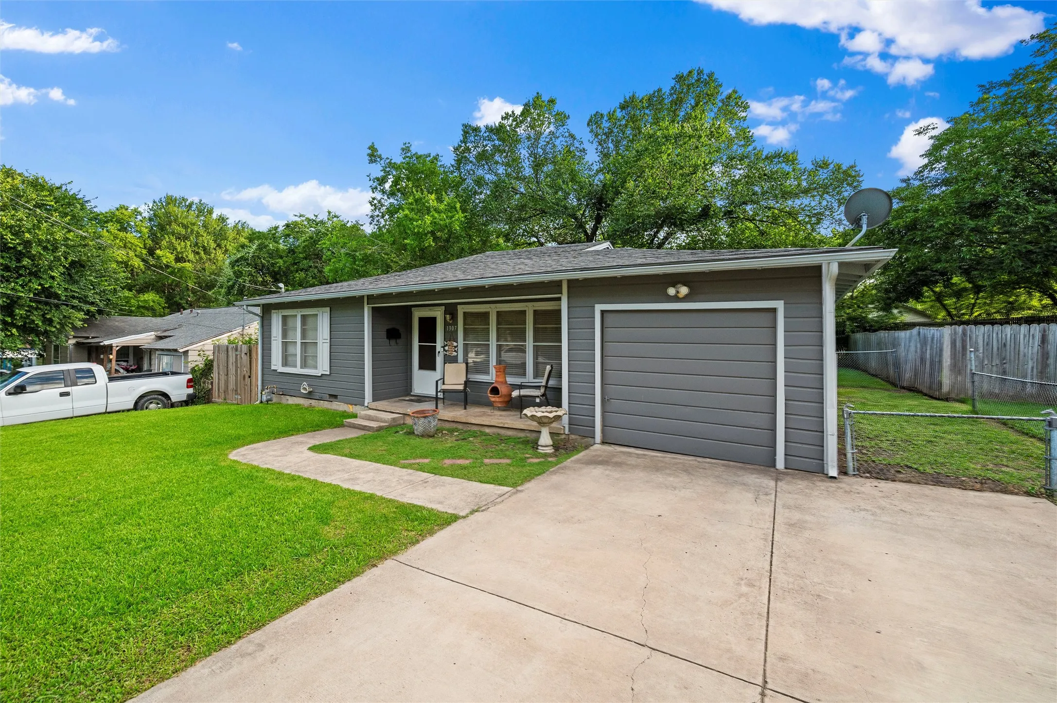 Front Exterior features gray lap siding with a composition shingle roof. Covered front porch and single-car attached garage complement the front elevation. Concrete driveway provides additional parking.