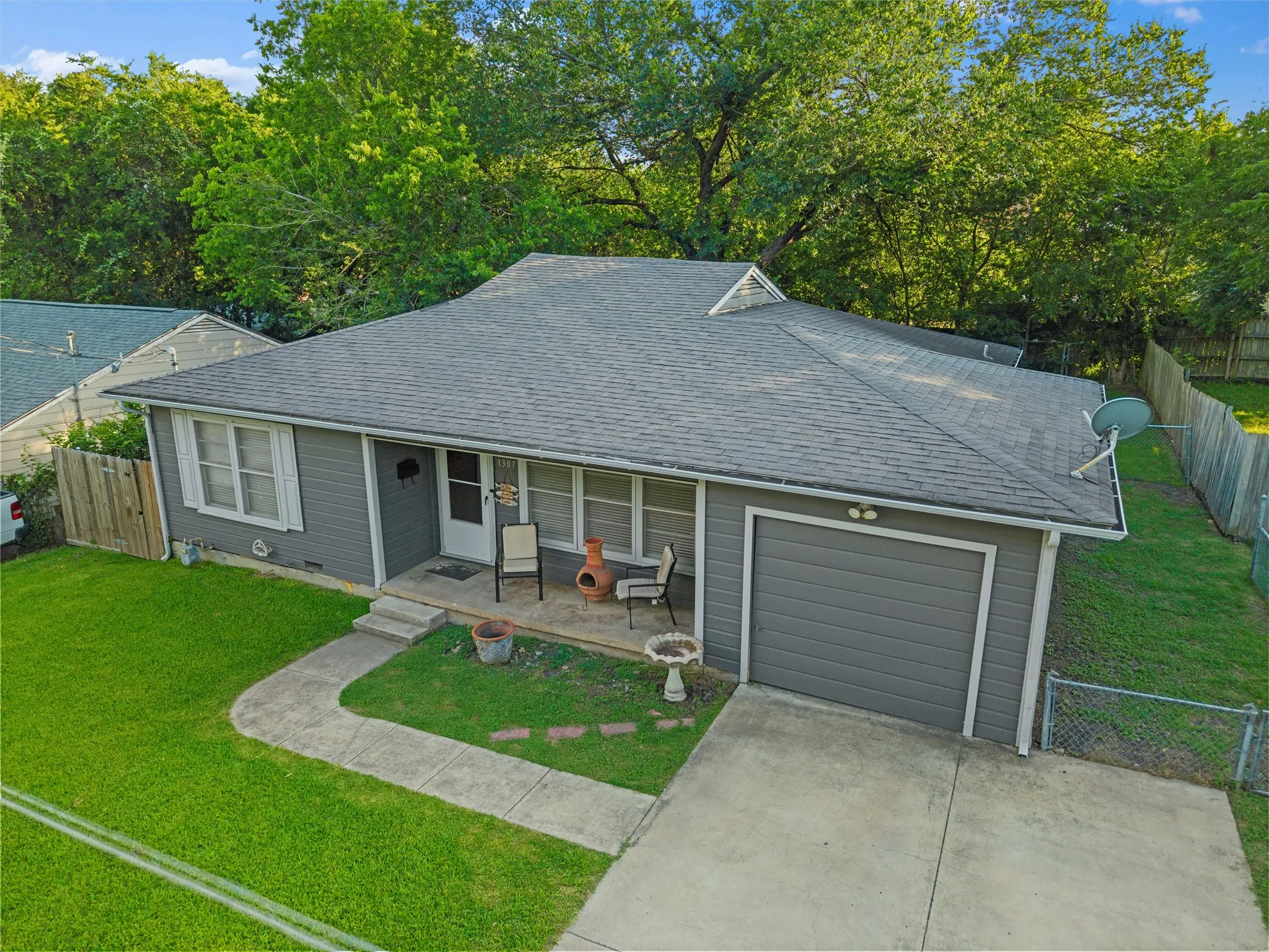 Aerial view showcases the home's location, surrounding mature trees, and neighborhood setting.