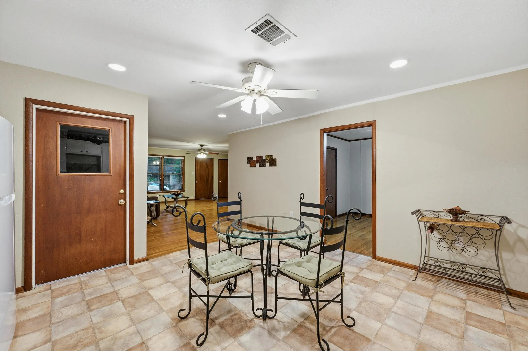 Eat-In Kitchen features recessed lighting and a ceiling fan with light fixture. Rear exterior door with window provides natural light and backyard access. Open layout connects directly to the living room. Tile flooring extends throughout.