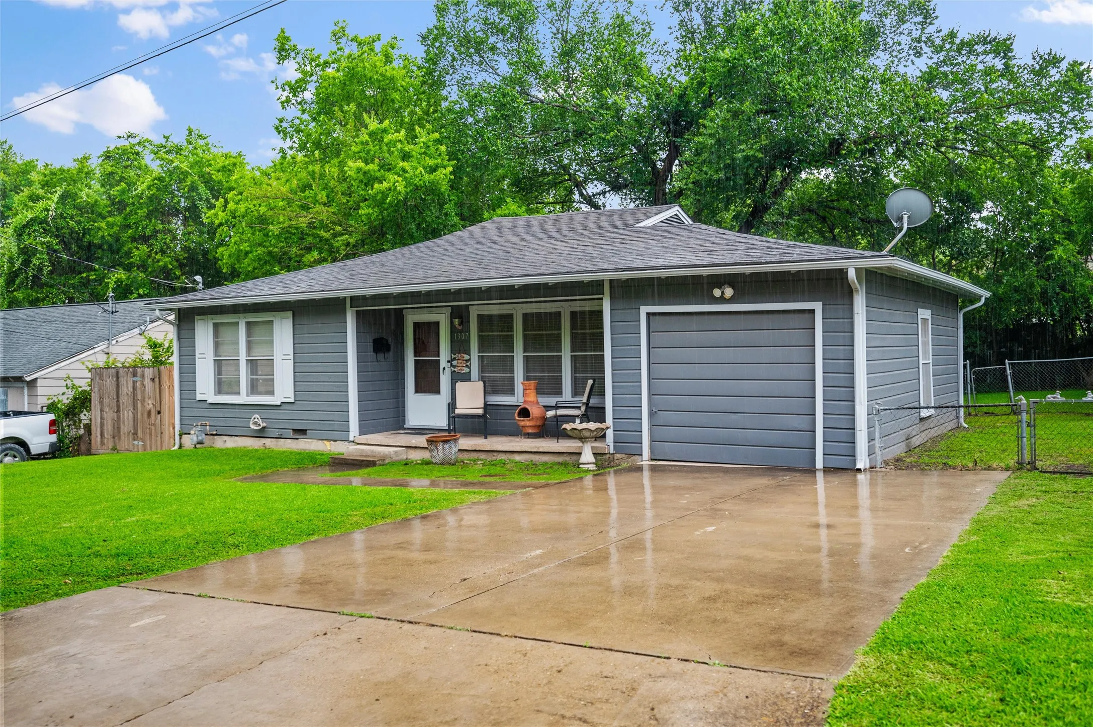 Front Exterior features gray lap siding with white trim and a composition shingle roof. Covered front porch leads to the main entrance. Single-car attached garage and concrete driveway complete the front elevation.