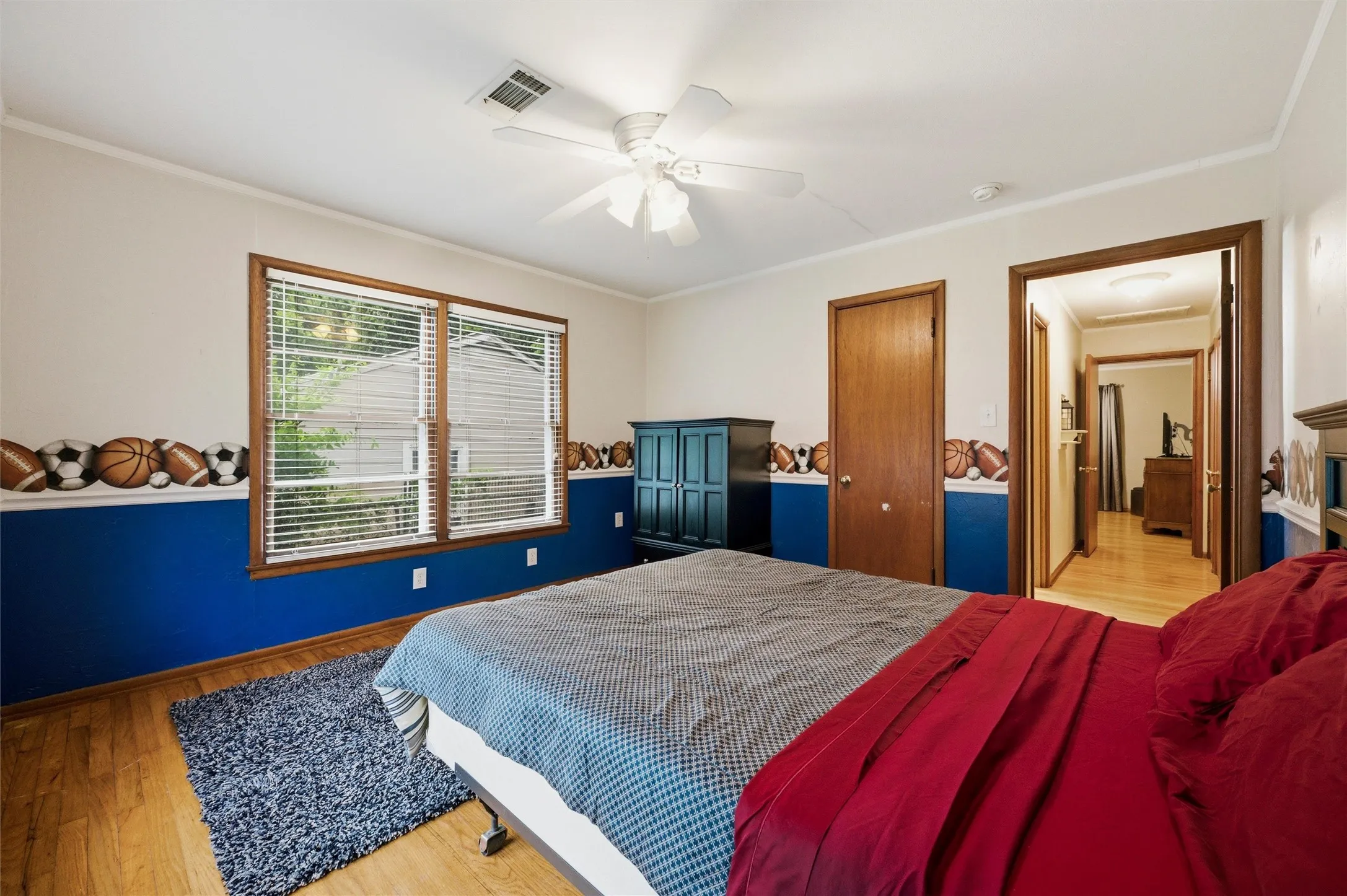 Secondary Bedroom features crown molding and a ceiling fan with light fixture. Double windows provide natural light. Closet door provides storage access. Hardwood flooring extends throughout.
