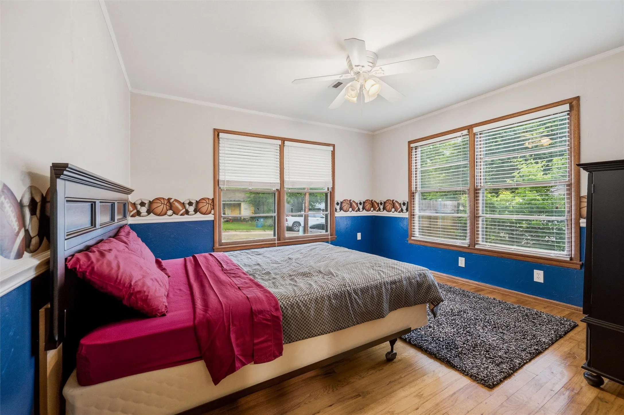 Secondary Bedroom features crown molding and a ceiling fan with light fixture. Double windows provide abundant natural light. Room connects directly to the eat-in kitchen. Hardwood flooring extends throughout.