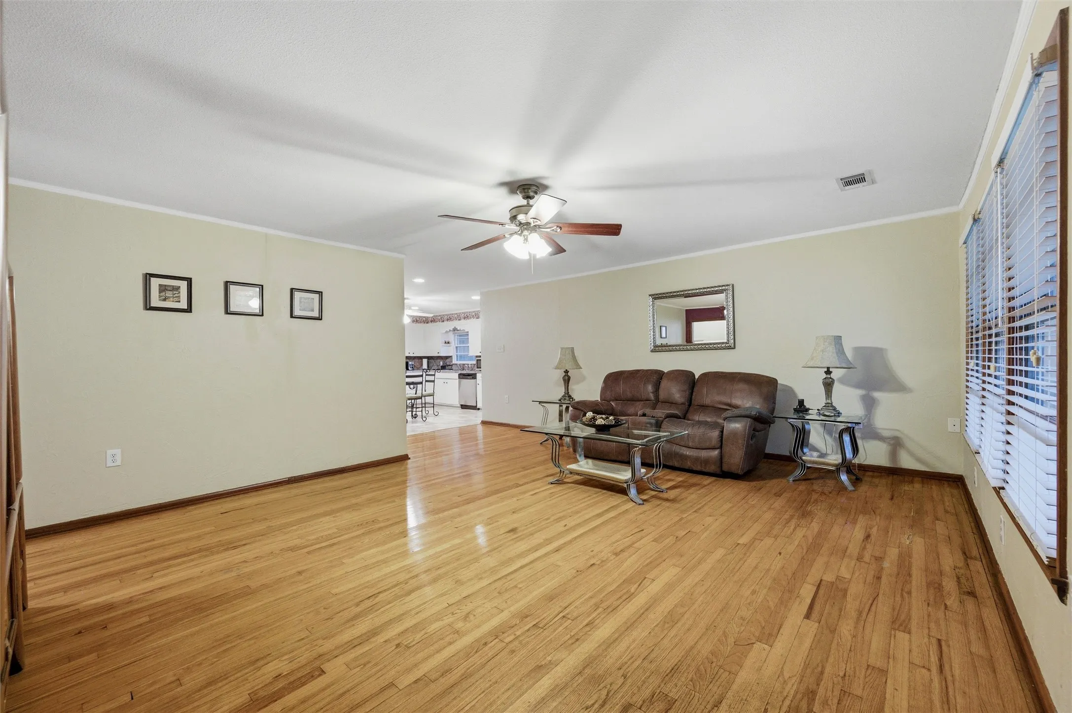 Living Room features crown molding and a ceiling fan with light fixture. Open-concept layout connects directly to the eat-in kitchen. Hardwood flooring extends throughout.