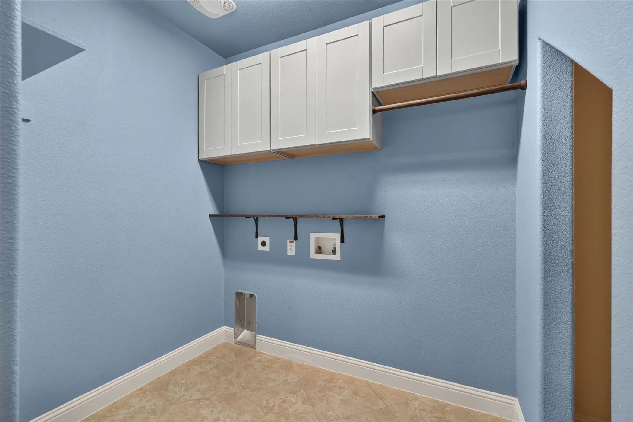 Laundry area featuring white shaker-style cabinetry, a hanging rod, appliance hookups, and tiled flooring
