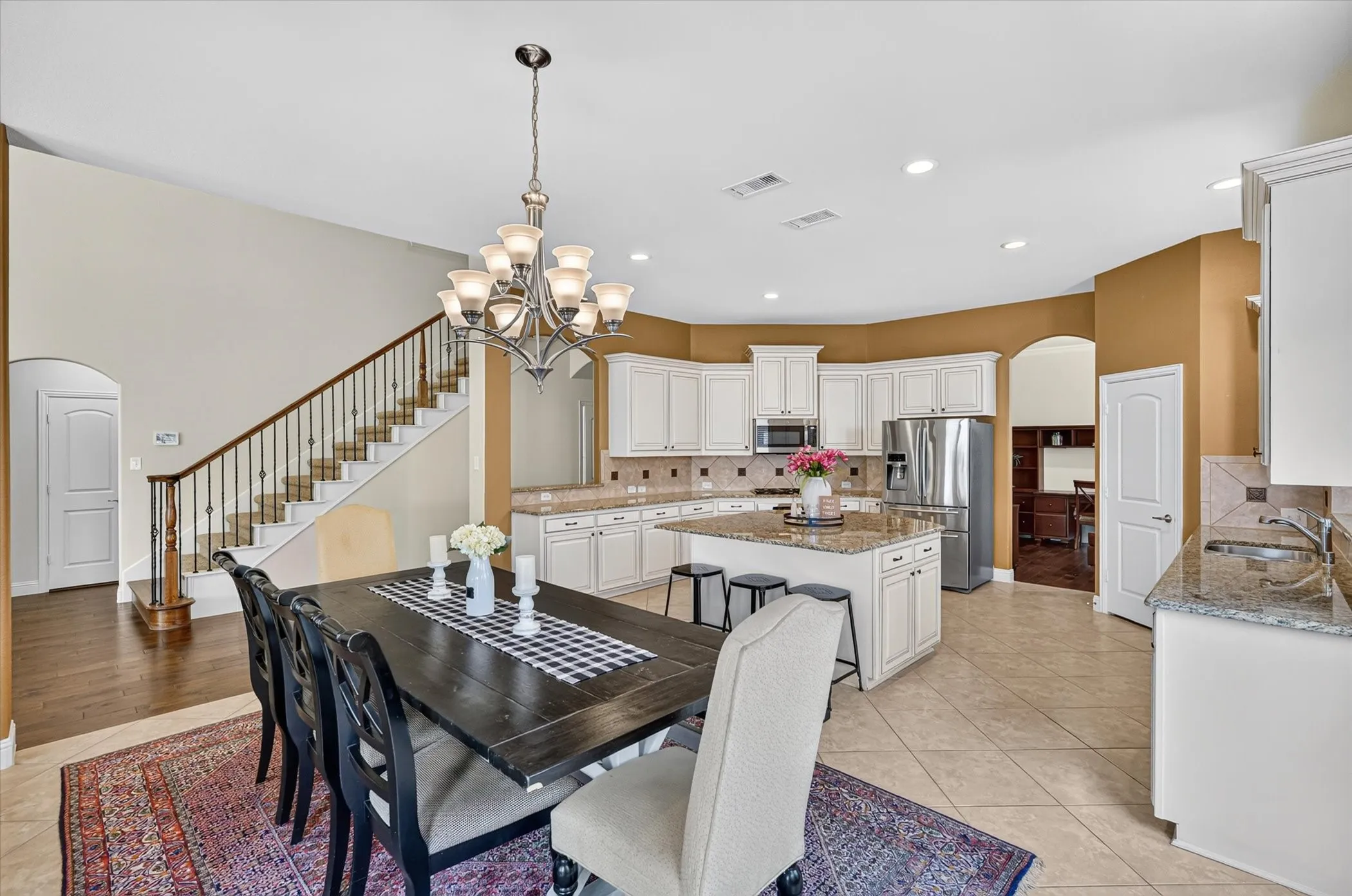 Open-concept kitchen featuring white cabinetry, granite countertops, and a central island with bar seating