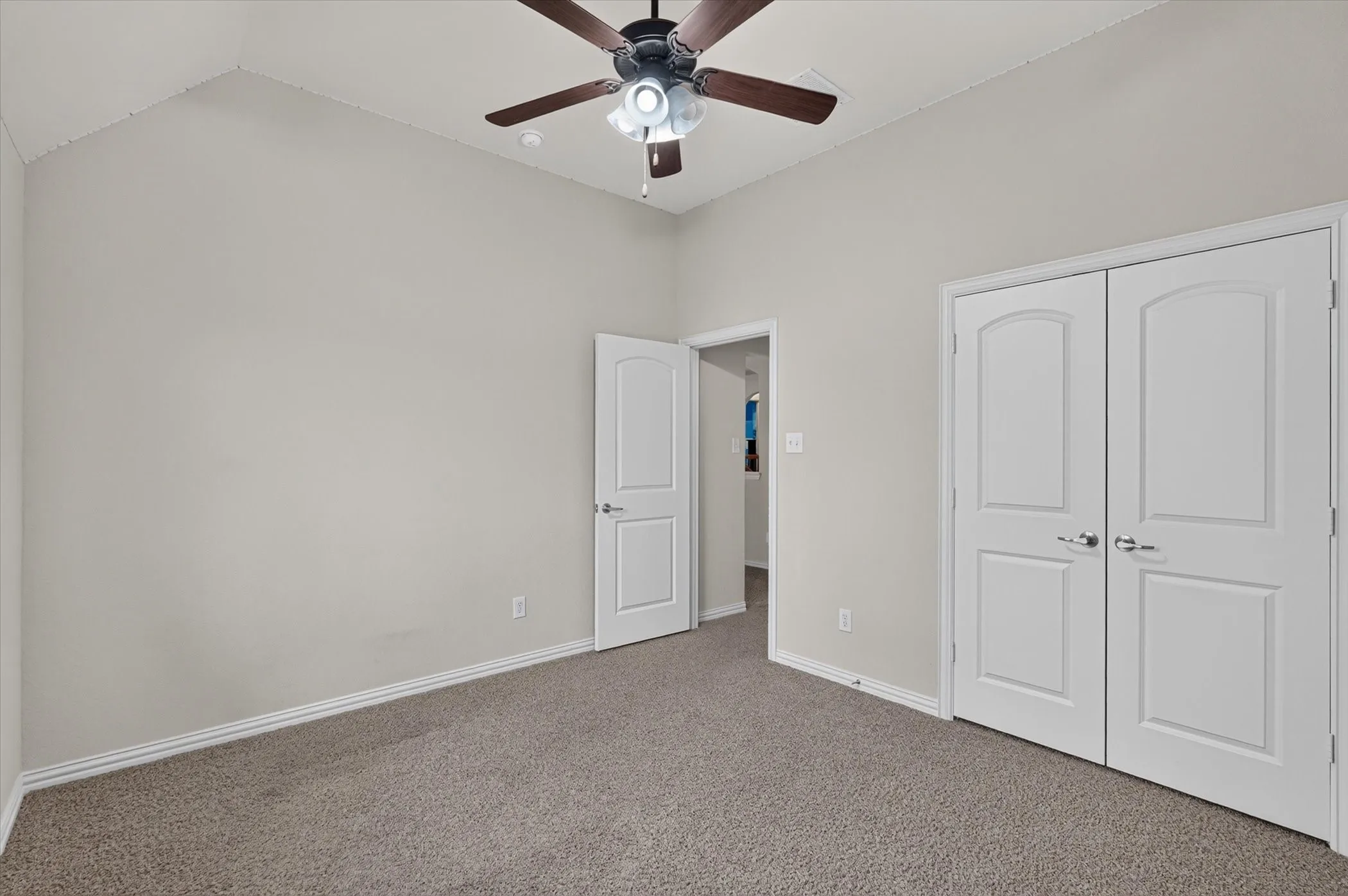 Carpeted room featuring a vaulted ceiling and a ceiling fan with integrated lighting