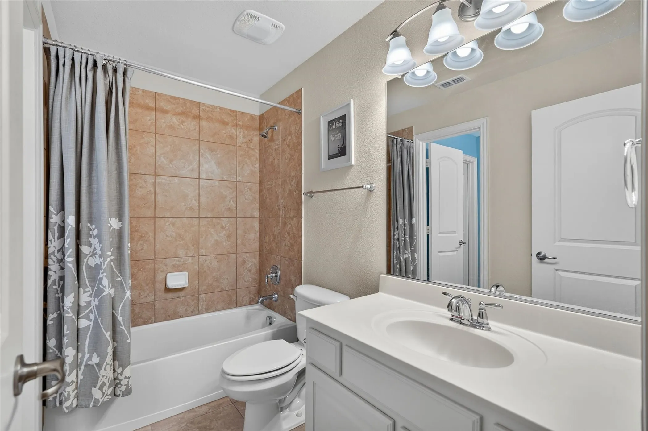 Bathroom featuring a white vanity with integrated sink, chrome faucet, and a large wall-mounted mirror