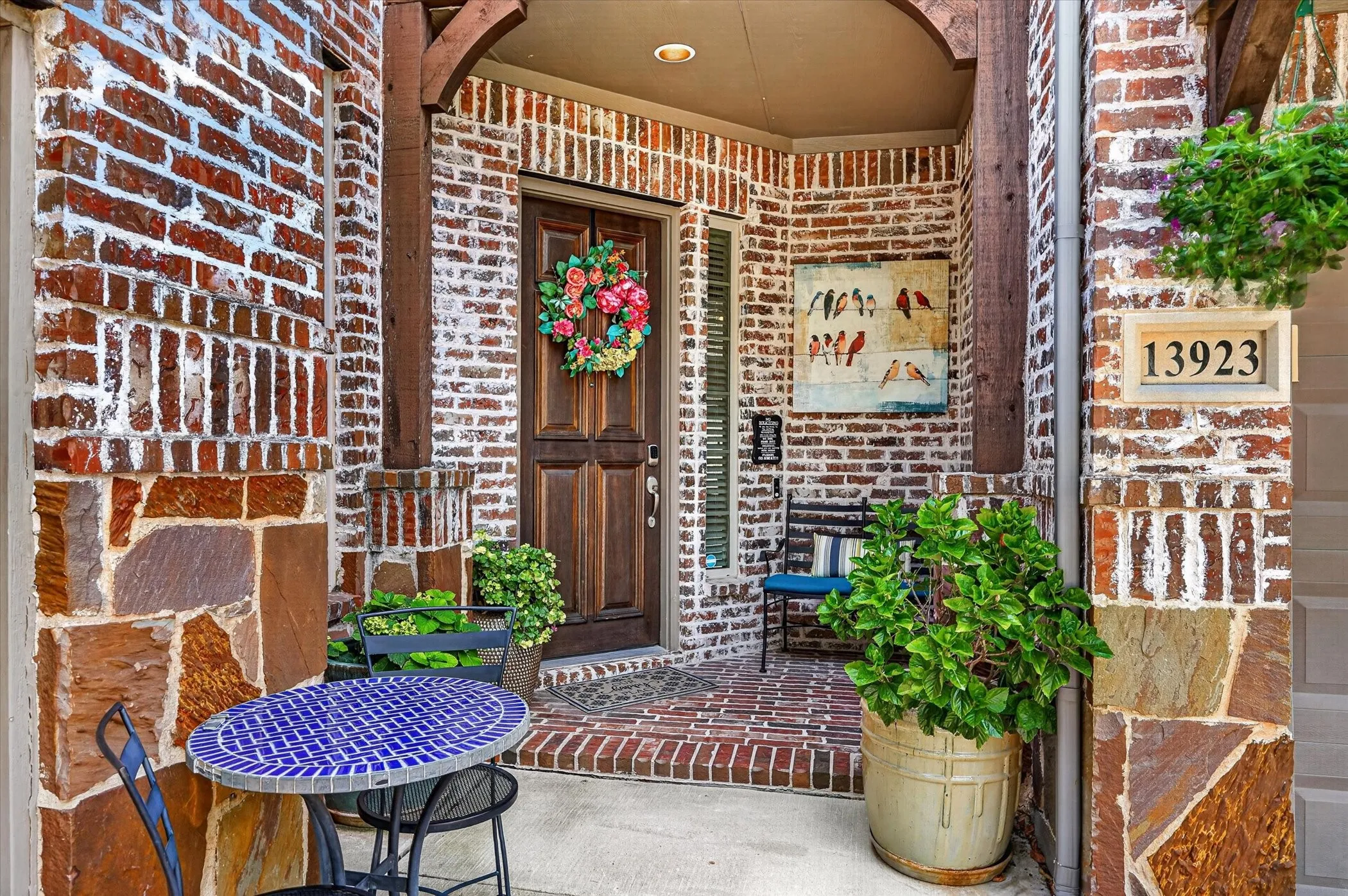 Entryway featuring a paneled wood door, brick facade with stone accents, brick flooring, and a recessed porch