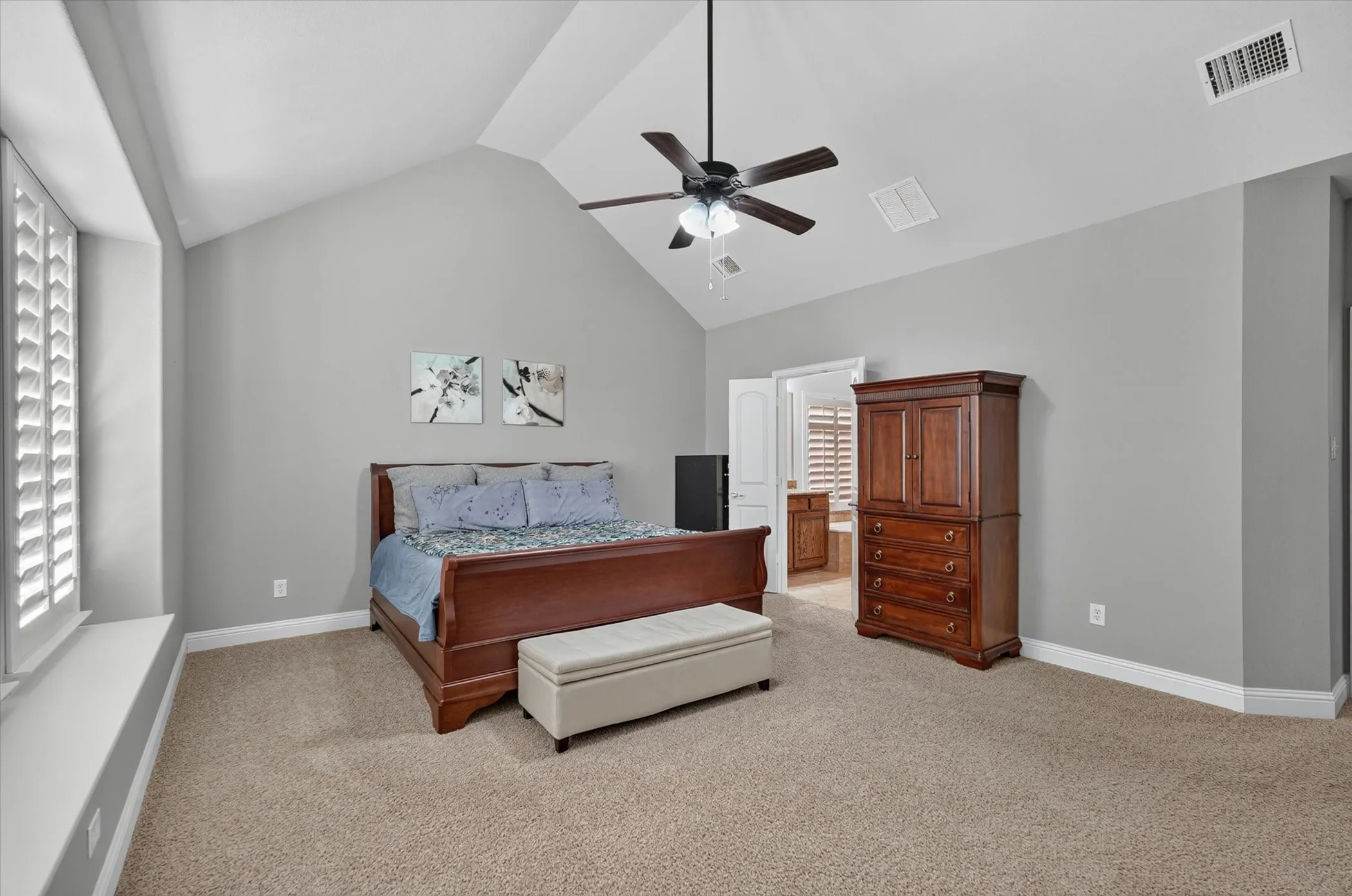 Vaulted ceiling with a ceiling fan, neutral carpet flooring, and plantation shutters on a deep window sill