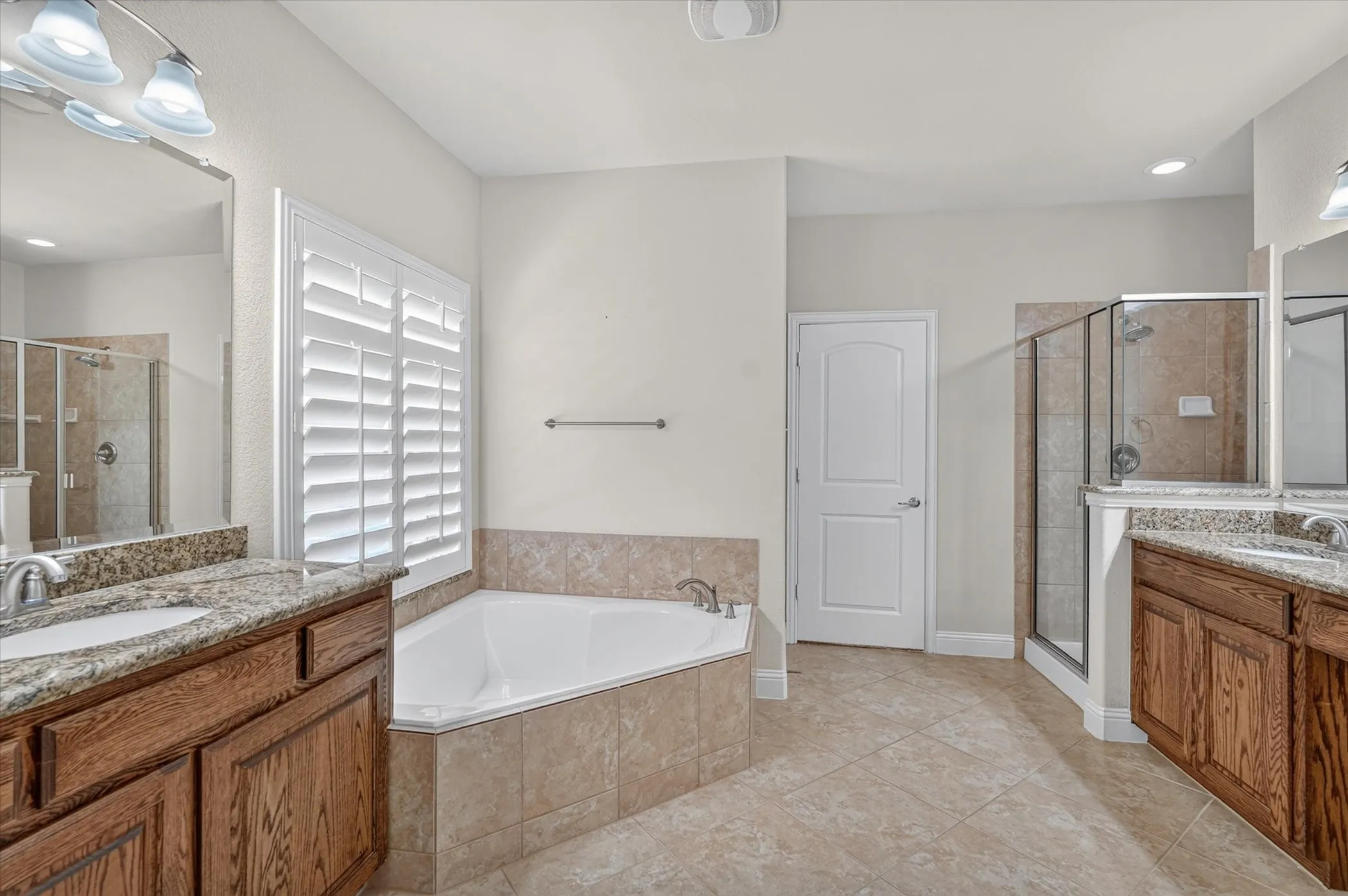 Dual wood-finish vanities with granite countertops and undermount sinks