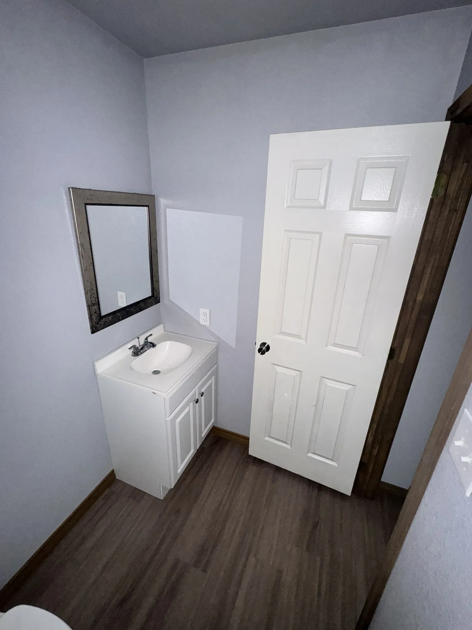 Bathroom featuring a vanity with white cabinetry, a single basin sink, and a framed mirror