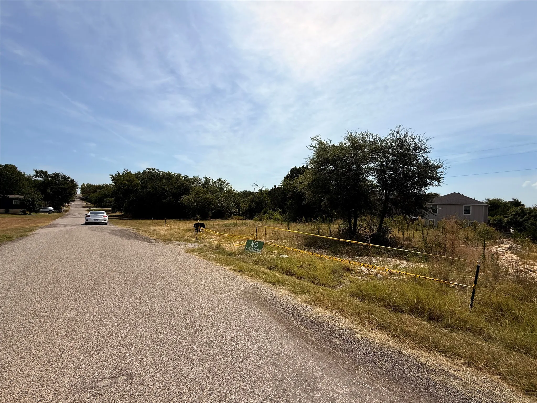 Expansive undeveloped parcel featuring established trees and a defined property marker