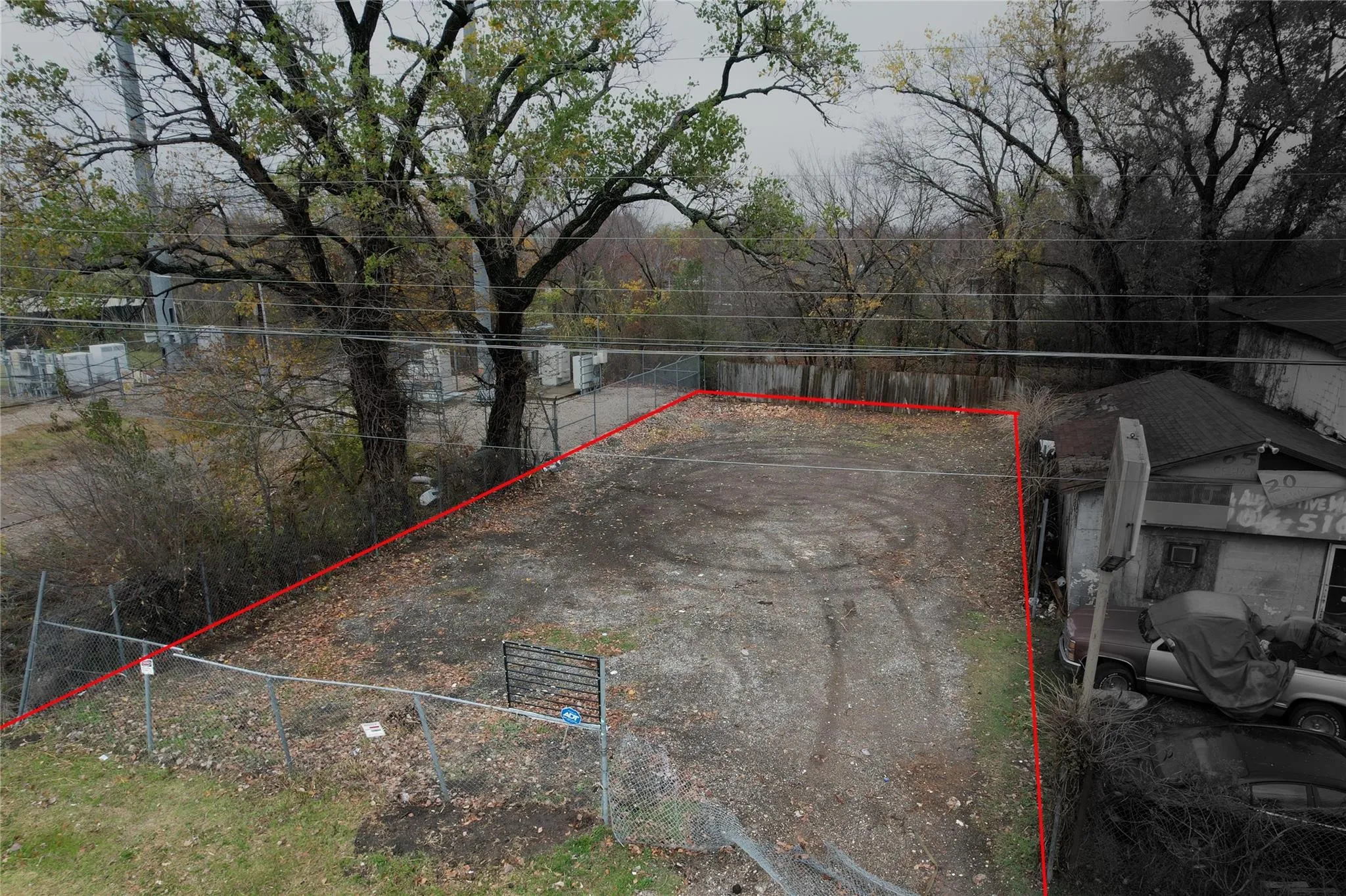 Fenced lot featuring a gravel surface and mature perimeter trees