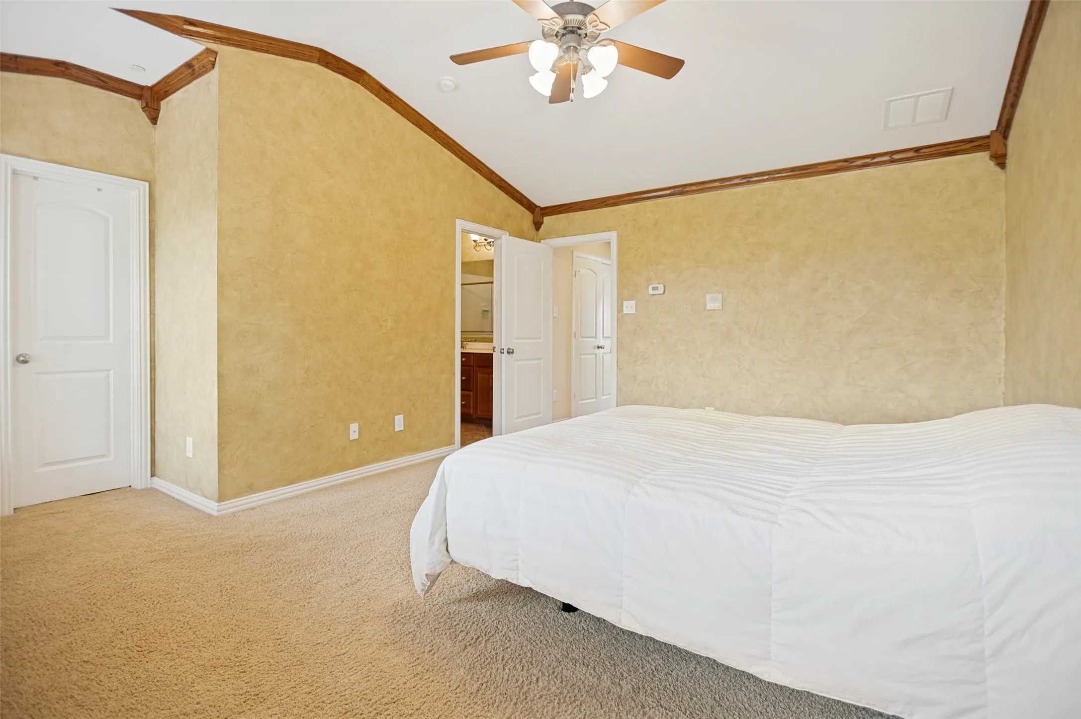 Carpeted room featuring a vaulted ceiling with exposed wood beams, a ceiling fan with integrated lighting, and textured wall finishes