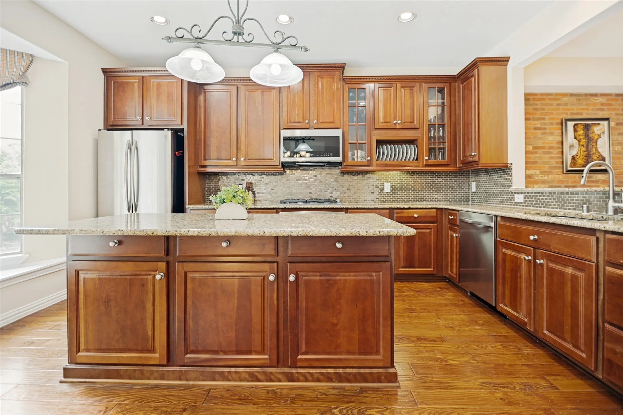 Kitchen featuring wood-finish flooring, warm wood cabinetry, and speckled stone countertops