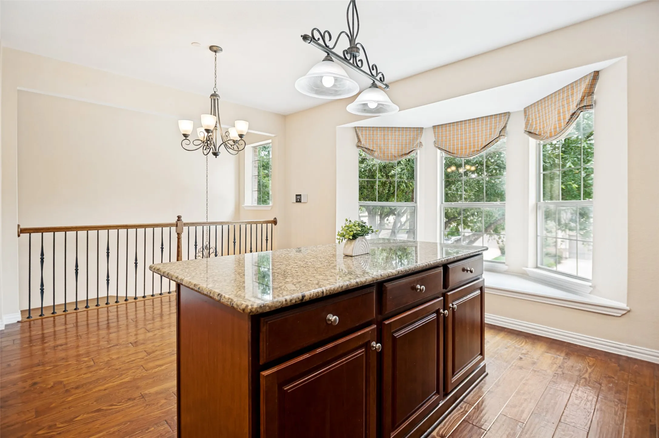 Kitchen island with a granite countertop, dark wood cabinetry, and chrome hardware