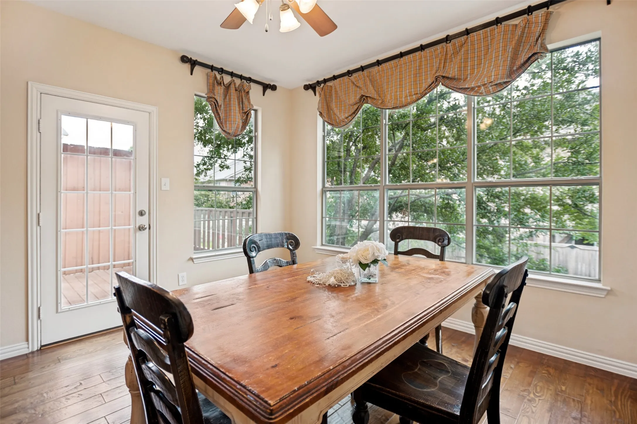 Dining area featuring hardwood-finish flooring, a multi-pane glass door, and a large multi-pane window with exterior views