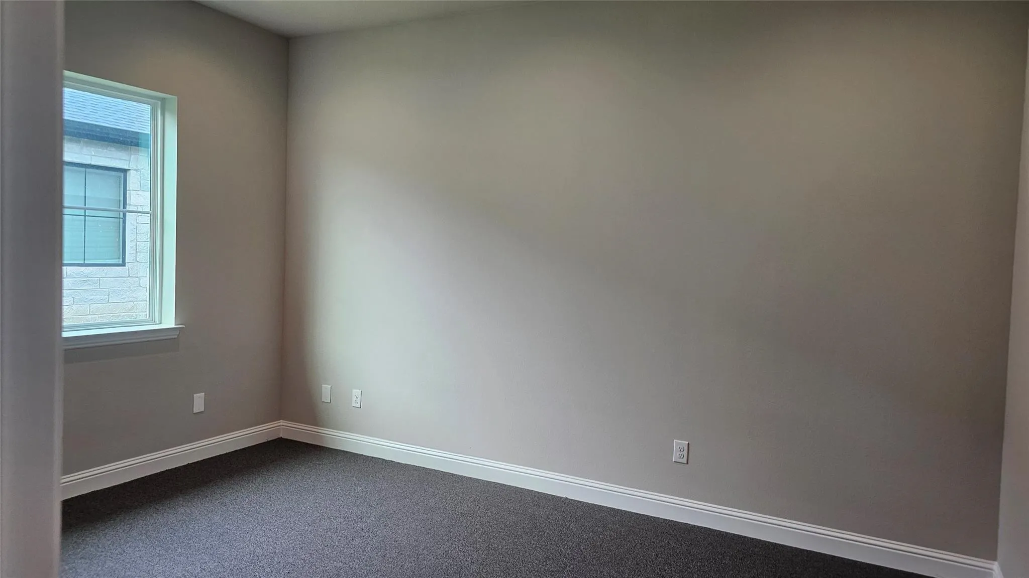 Room featuring a single window, neutral wall paint, and dark carpet