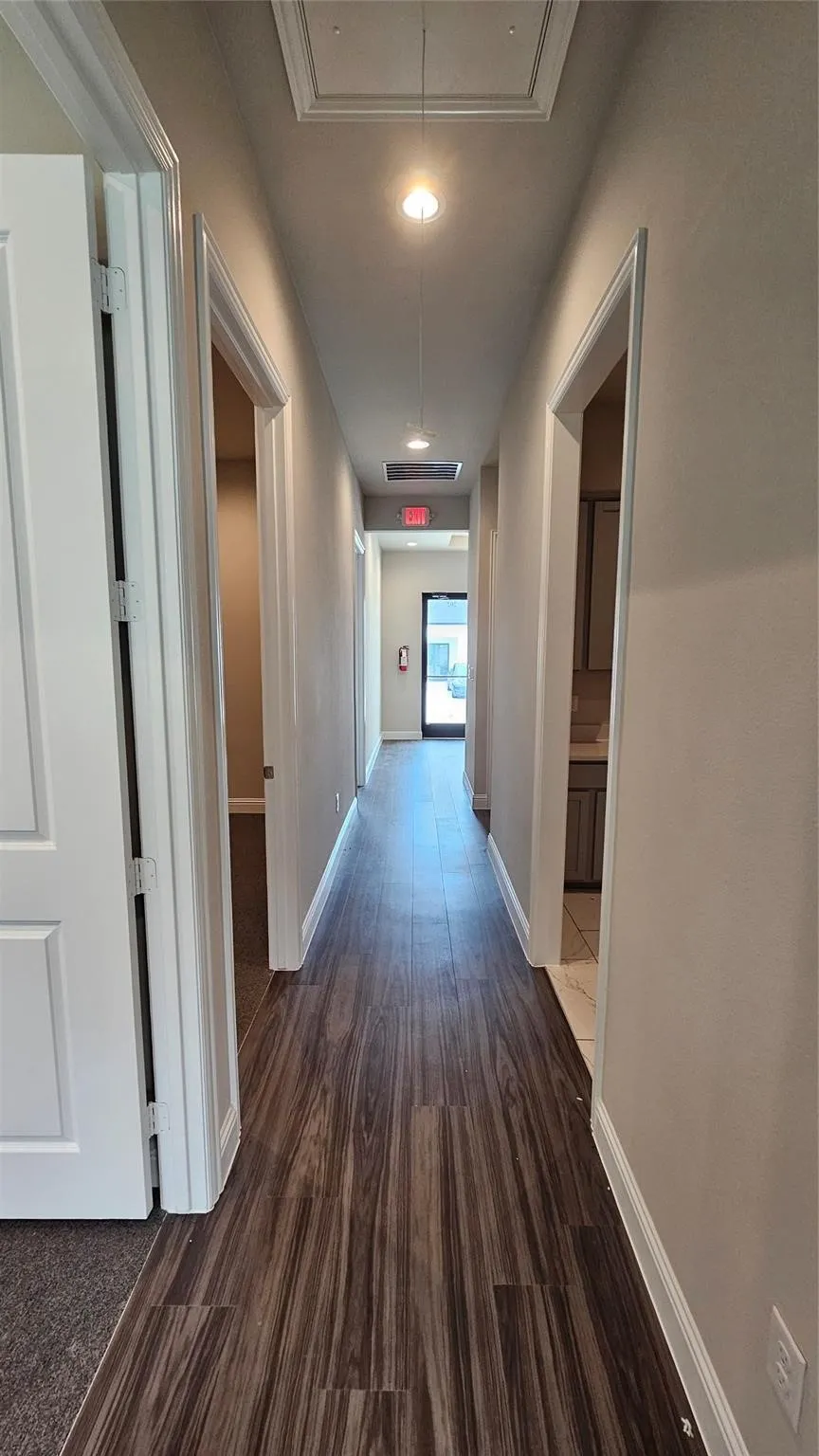 Corridor featuring wood-finish flooring, white baseboards, recessed lighting, and crisp white doors