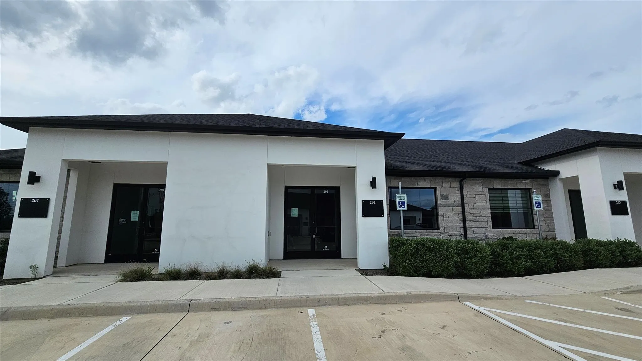 Contemporary commercial exterior featuring a white facade and a dark shingled roof