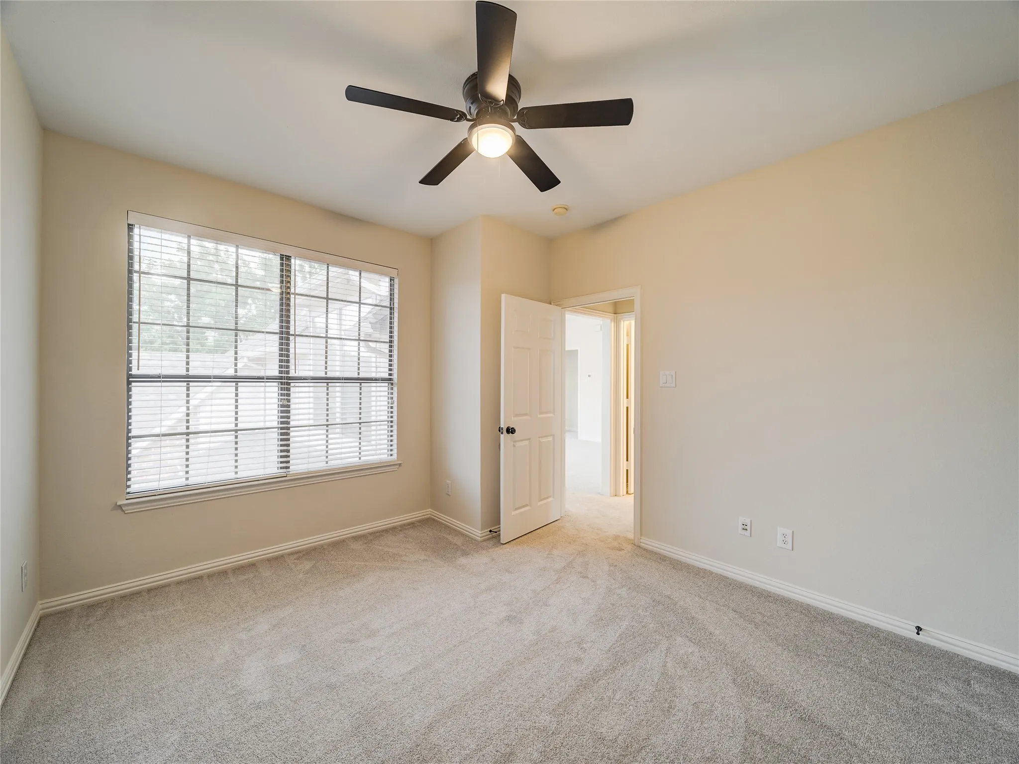 Room featuring light neutral wall paint, light-toned carpet flooring, and a multi-pane window with blinds