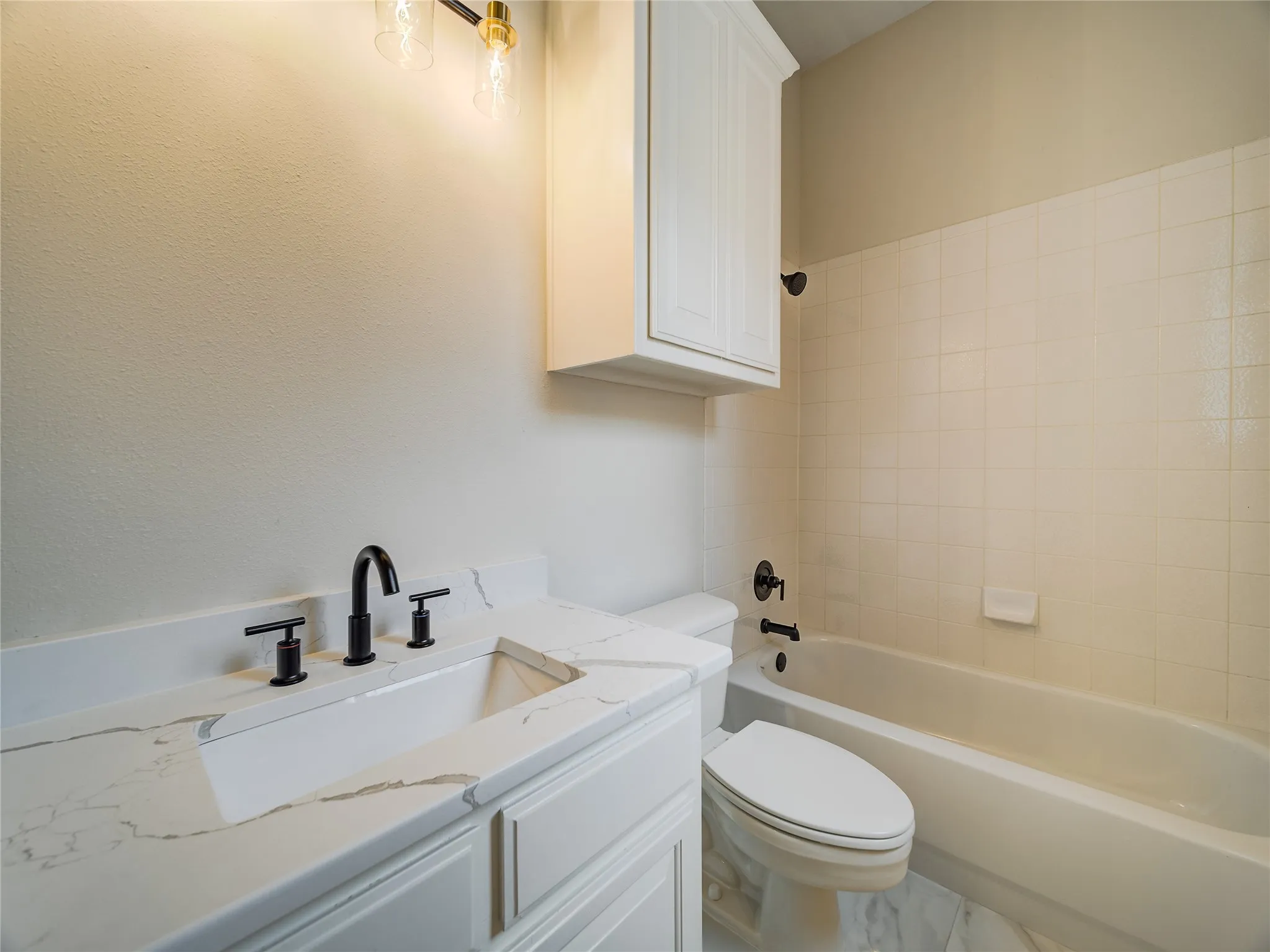 Bathroom vanity featuring a solid surface countertop with an integrated sink and matte black fixtures