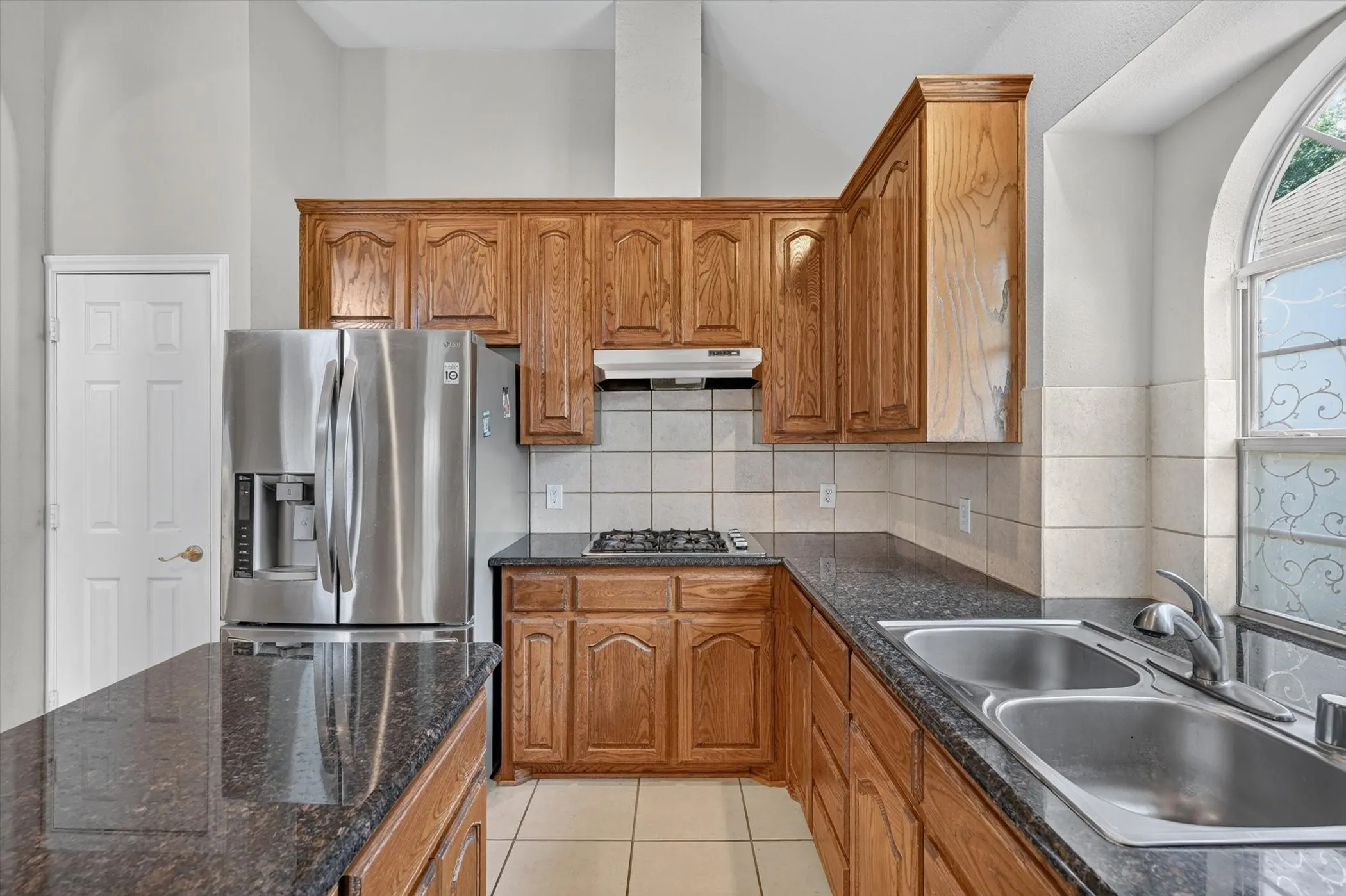 Kitchen featuring wood cabinetry, dark speckled countertops, and stainless steel appliances including a built-in microwave, oven, and dishwasher
