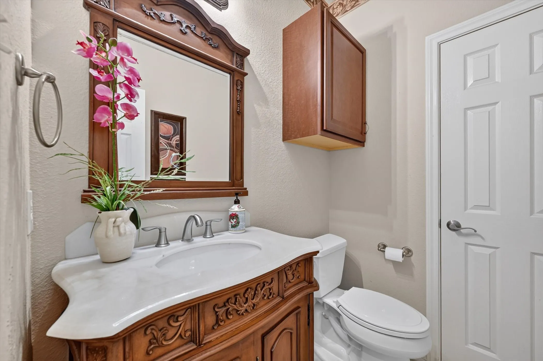 Bathroom vanity featuring a carved wood-finish base, integrated basin, and a light-toned countertop