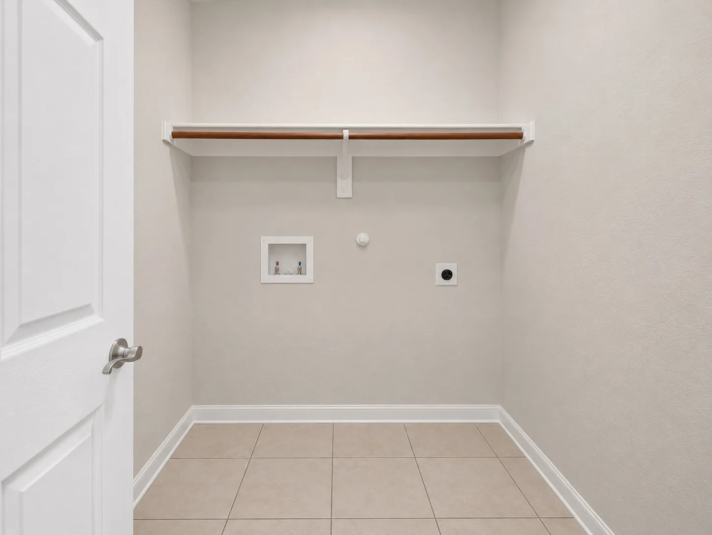 Utility room featuring tile flooring, a built-in shelf with a clothing rod, and a washing machine hookup
