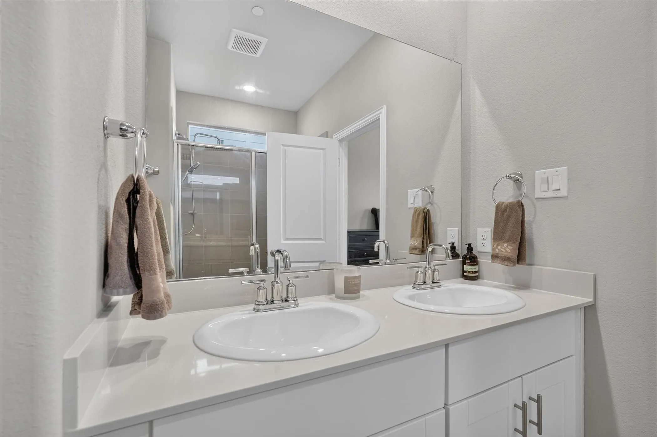 Spacious bathroom featuring a double vanity with undermount sinks, chrome fixtures, and a large wall-mounted mirror