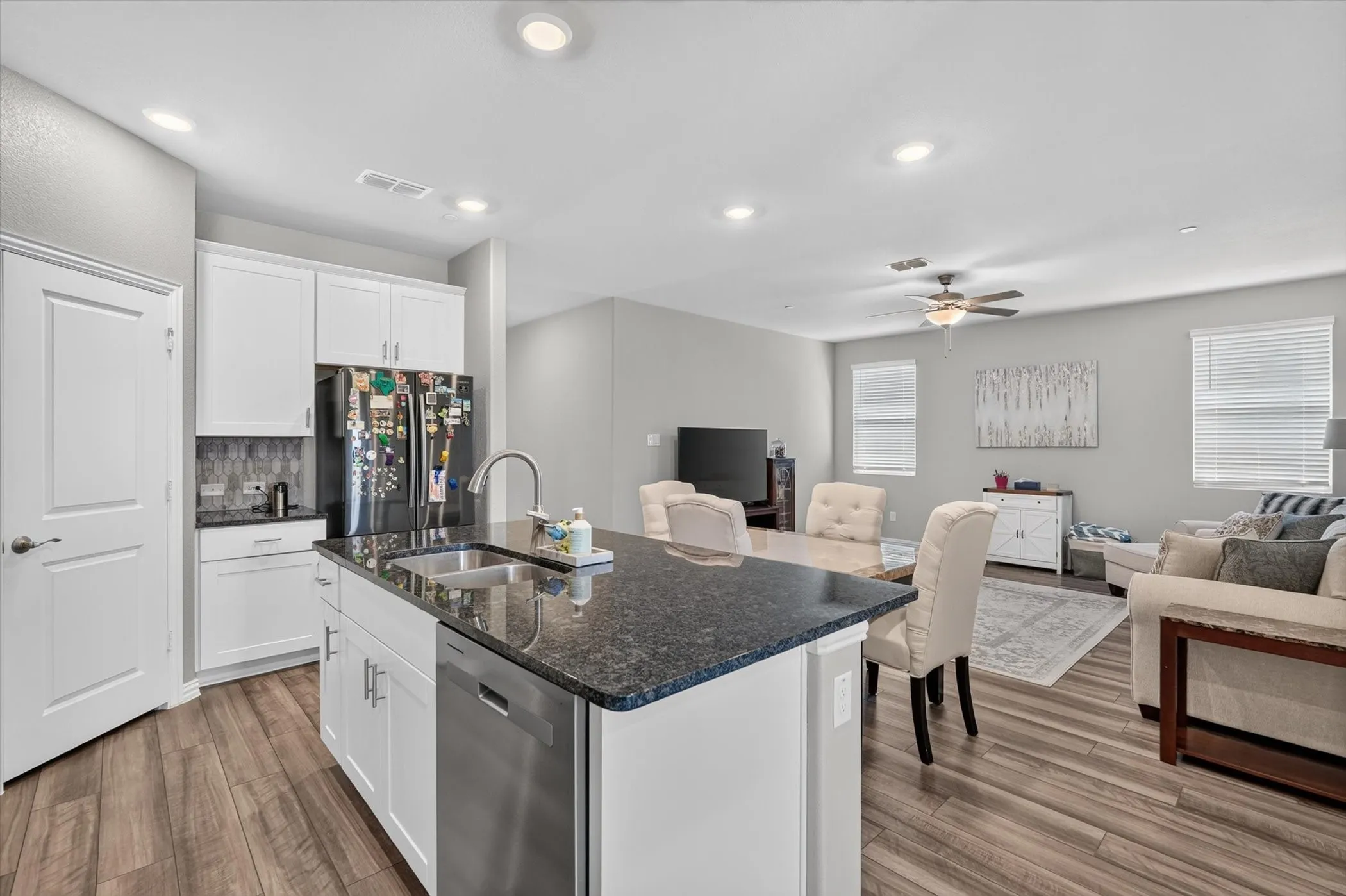 Kitchen island featuring a stainless steel sink, dark stone countertop, and integrated dishwasher
