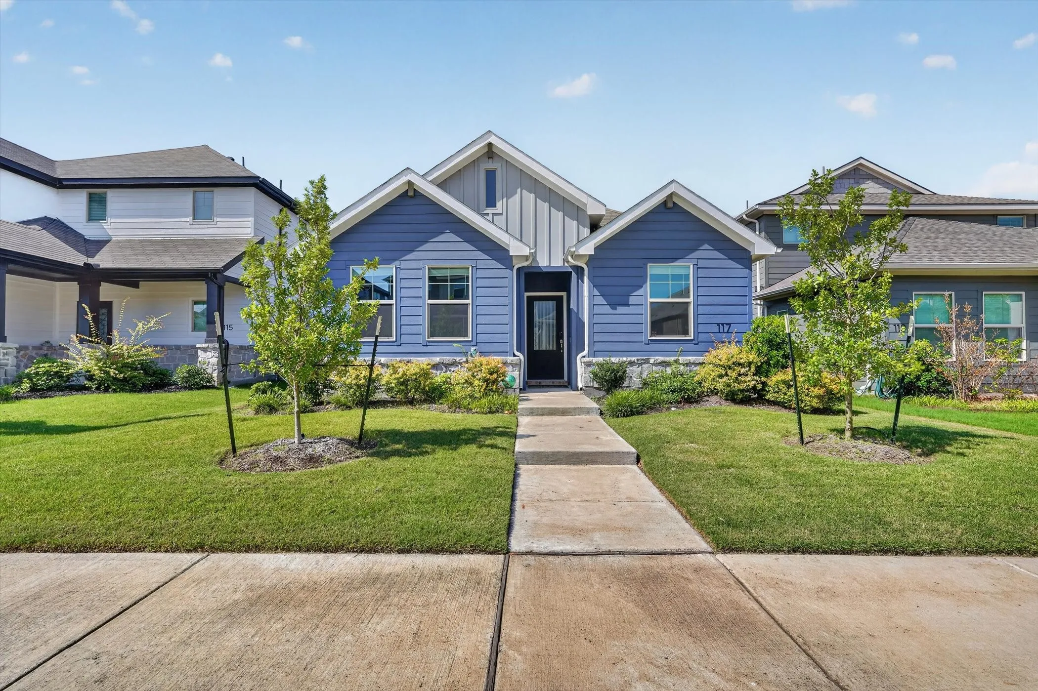 Contemporary facade featuring blue horizontal siding, stone accents, and a contrasting vertical siding gable