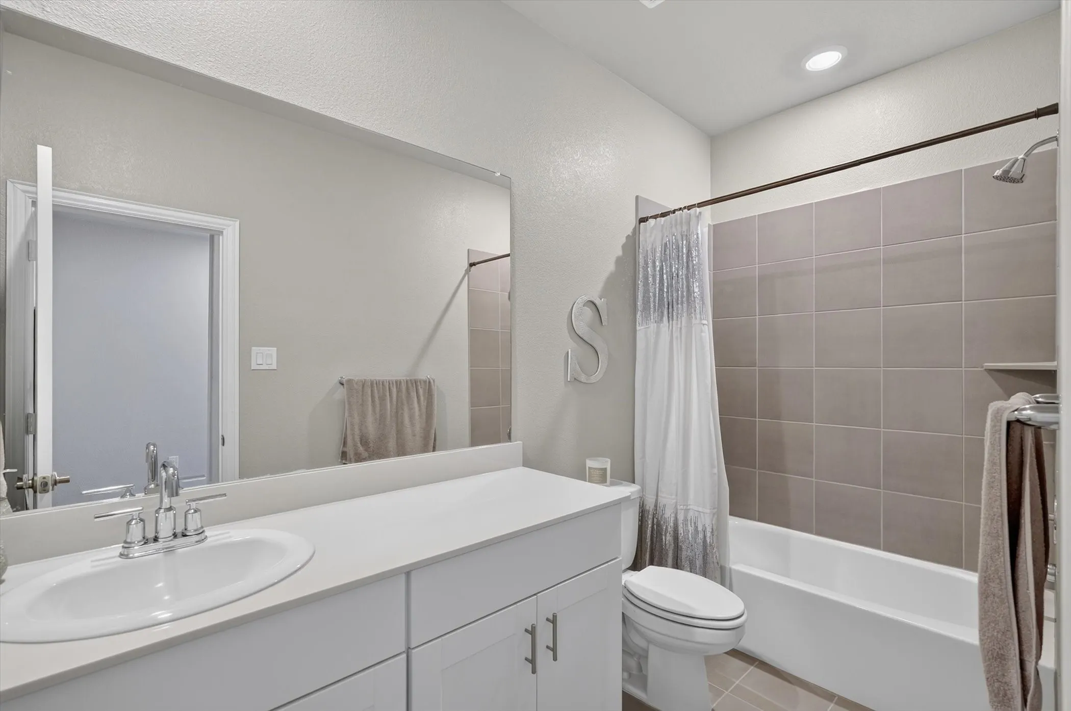 Bathroom featuring a single vanity with an integrated sink, polished chrome faucet, and white cabinetry