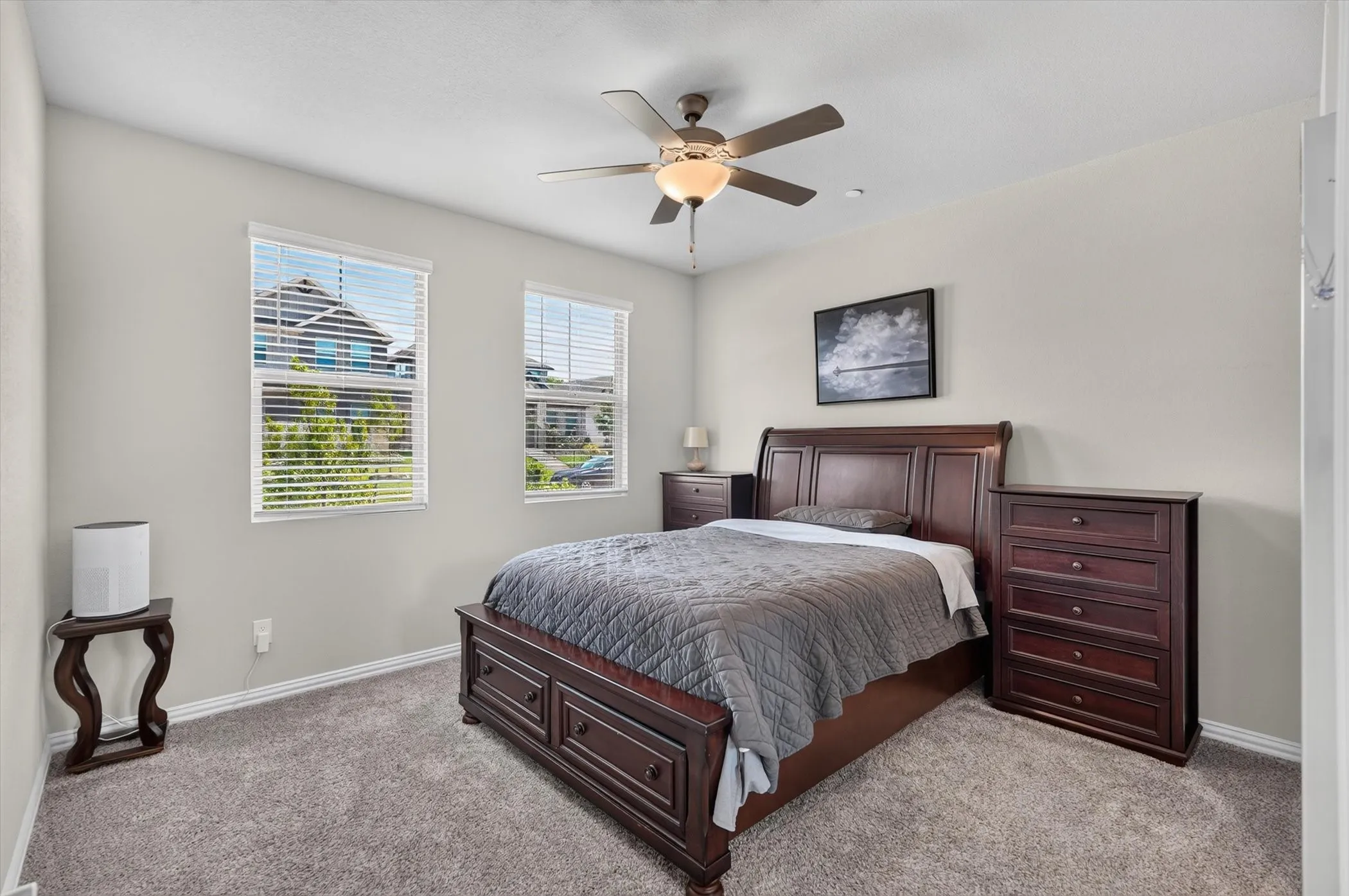 Carpeted room featuring two windows with horizontal blinds, a ceiling fan with integrated lighting, and a neutral wall color
