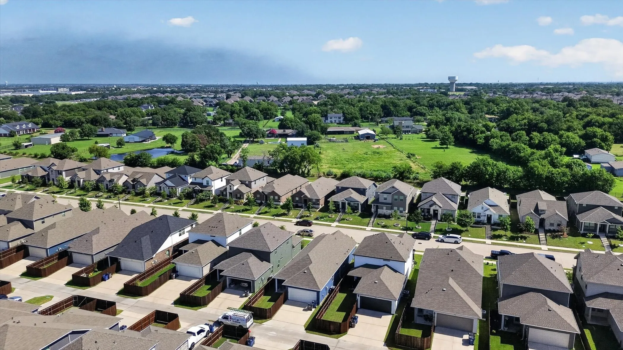 Aerial perspective showcasing a developed residential street with single-family homes, each featuring individual driveways and fenced backyard areas