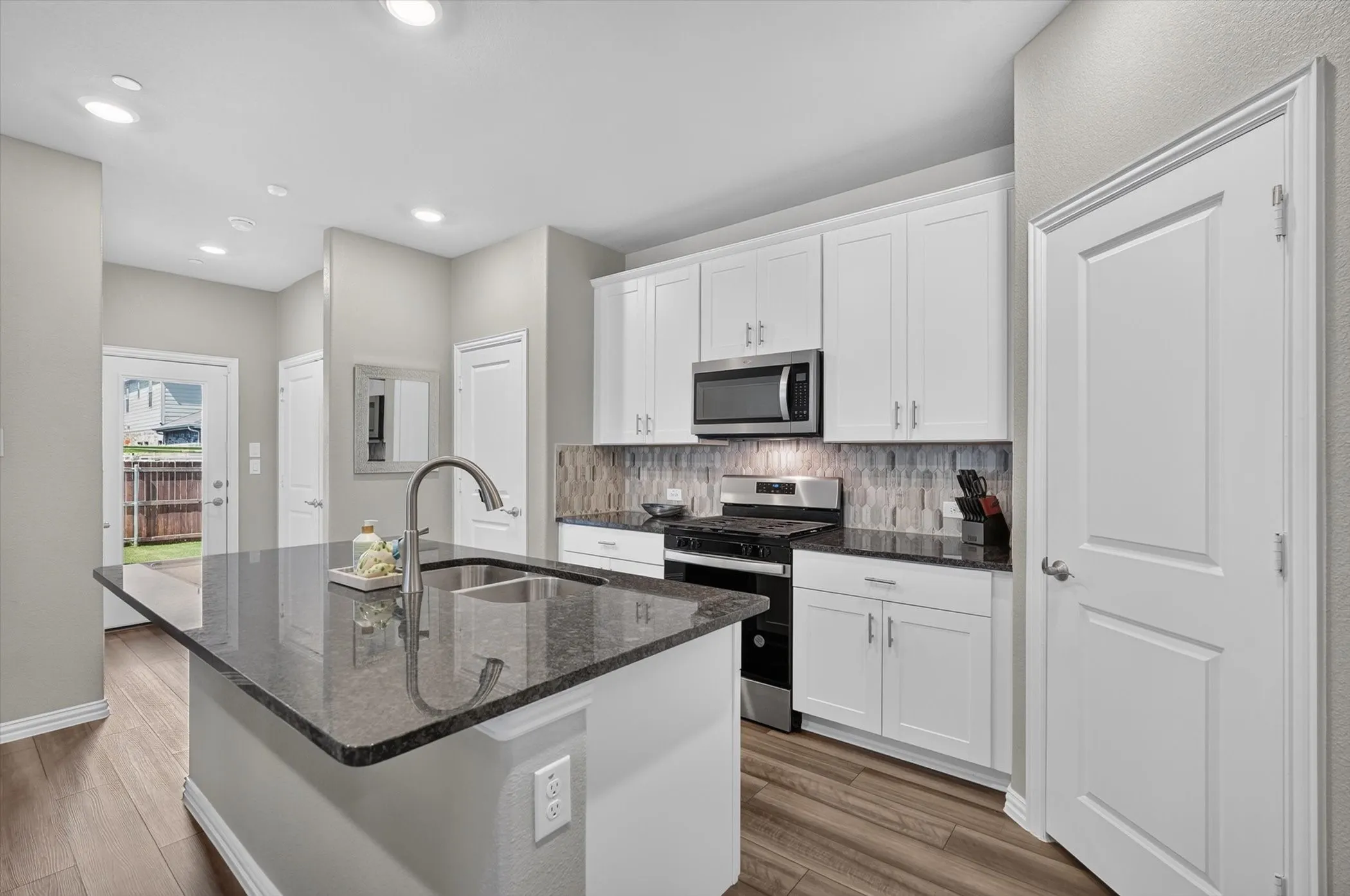 Kitchen island featuring a double basin sink and dark stone countertop