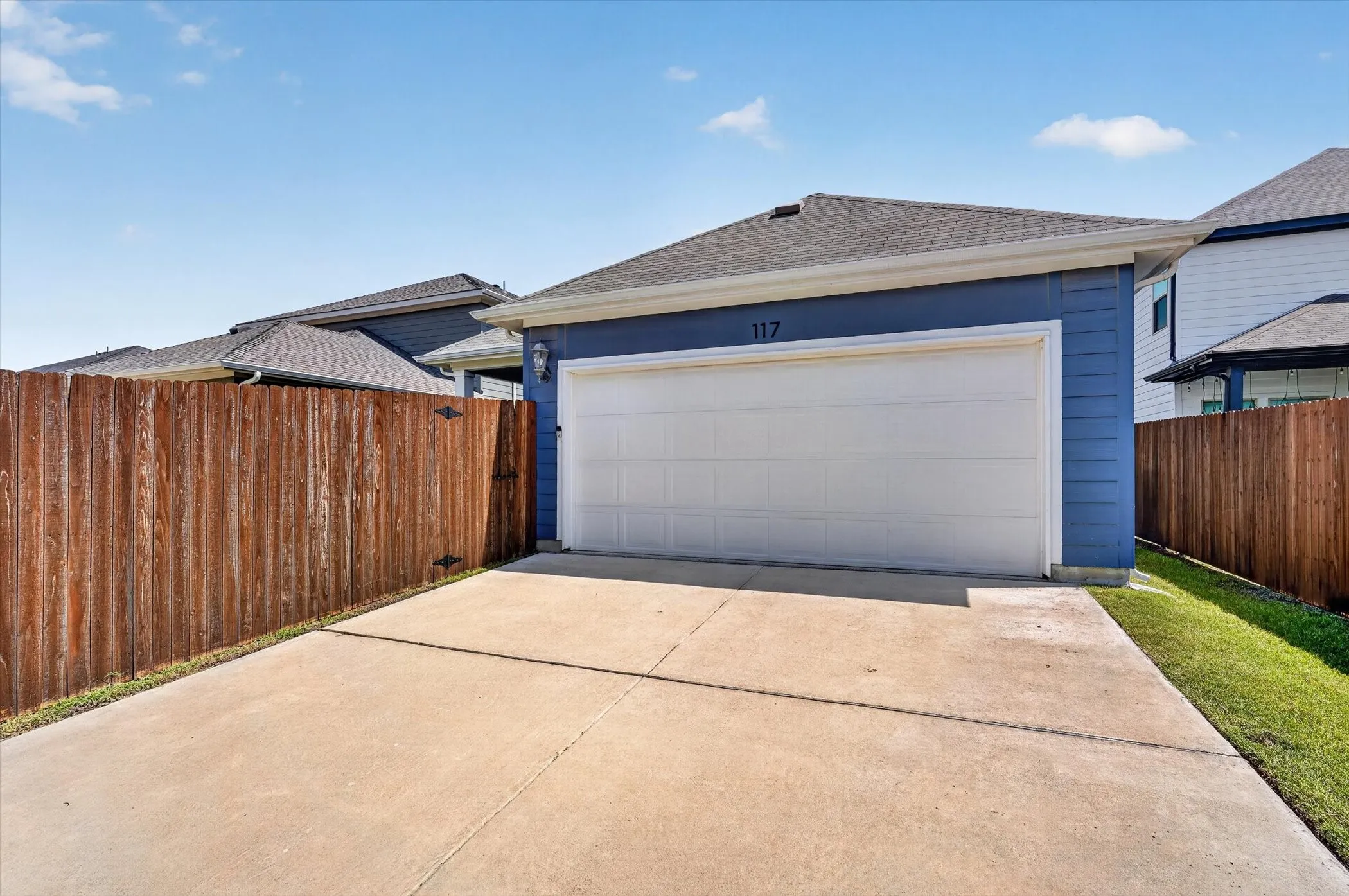 Concrete driveway leading to a detached garage with a white panel door and blue siding