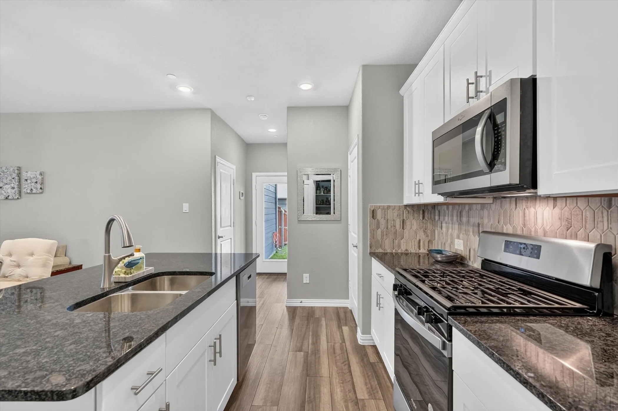 Kitchen featuring dark granite countertops, white cabinetry with silver hardware, and stainless steel appliances