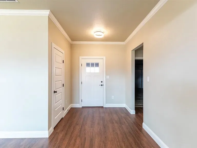 Entryway featuring wood-finish flooring, white baseboards, and crown molding