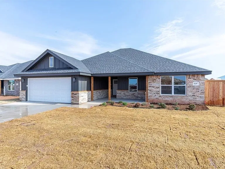Contemporary single-story home featuring a dark gray roofline, brick veneer, and vertical siding accents